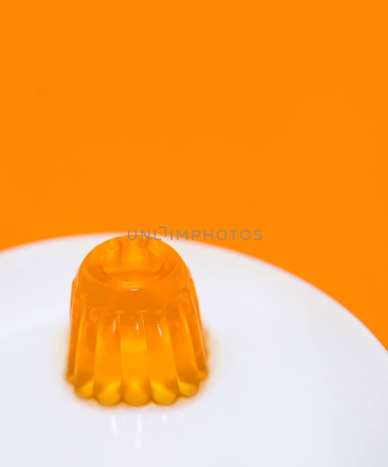 Close up of a orange gelatin on a white plate. Orange background.