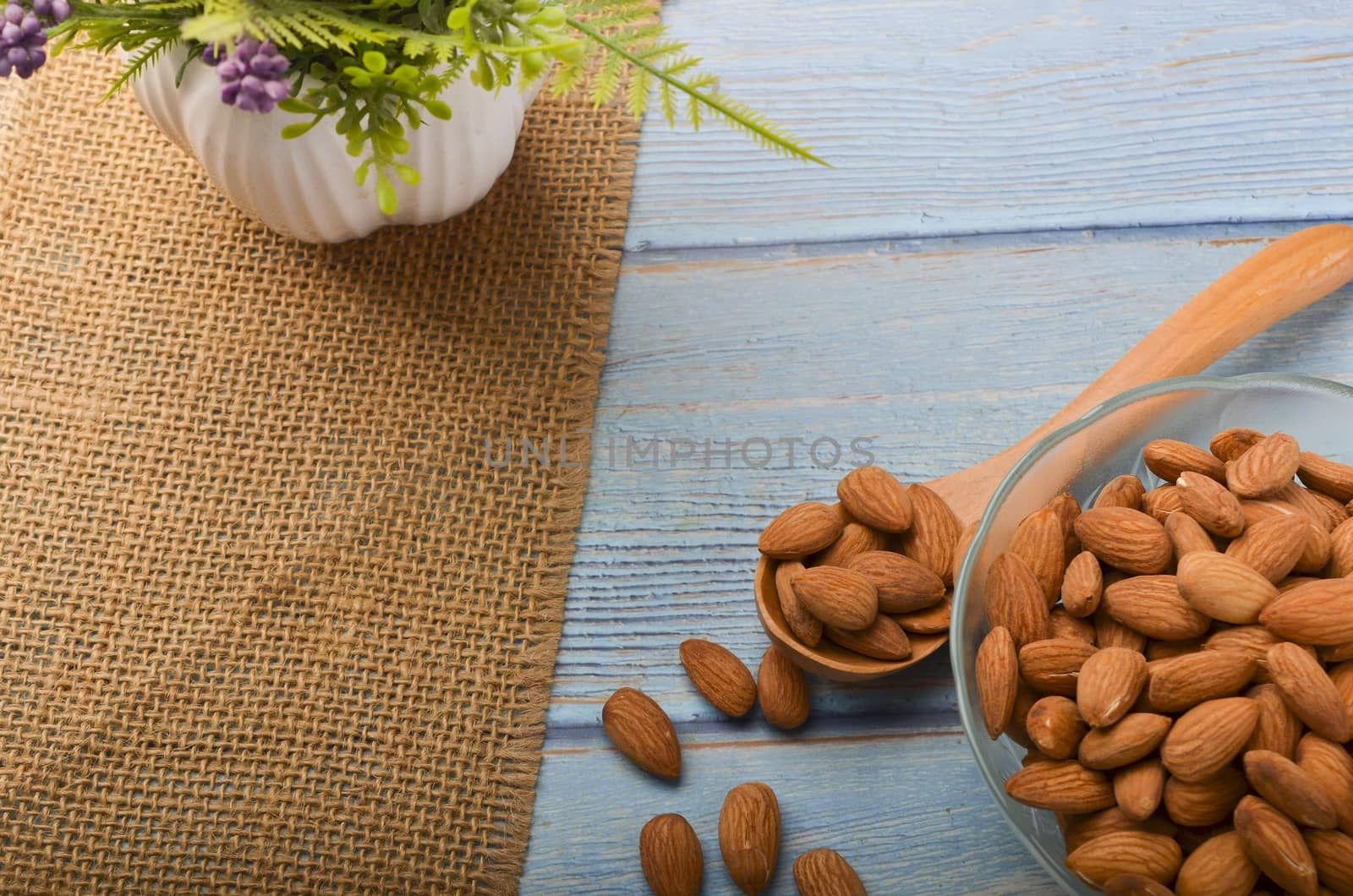 Almond nuts in a glass bowl on a wooden background. Selective focus.