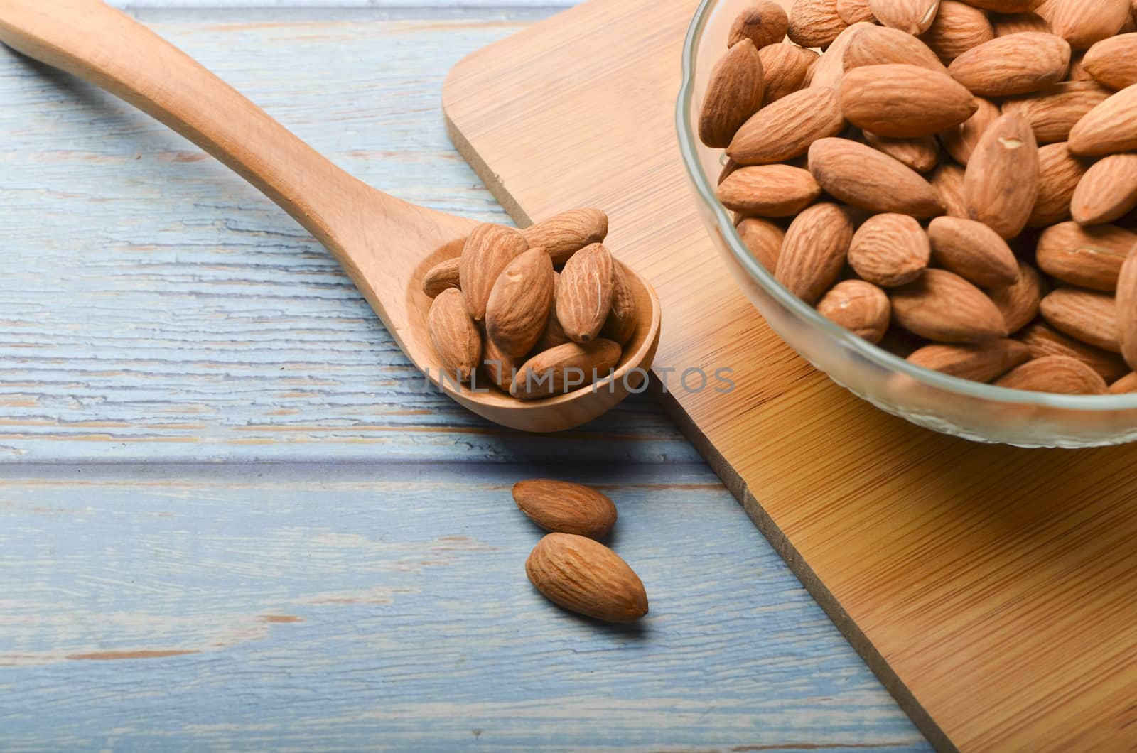 Almond nuts in a glass bowl on a wooden background. Selective focus.