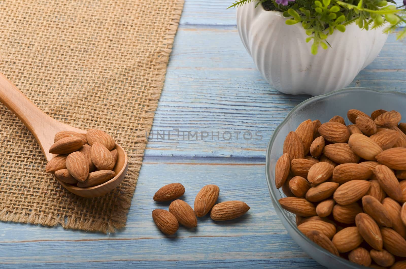 Almond nuts in a glass bowl on a wooden background. Selective focus.