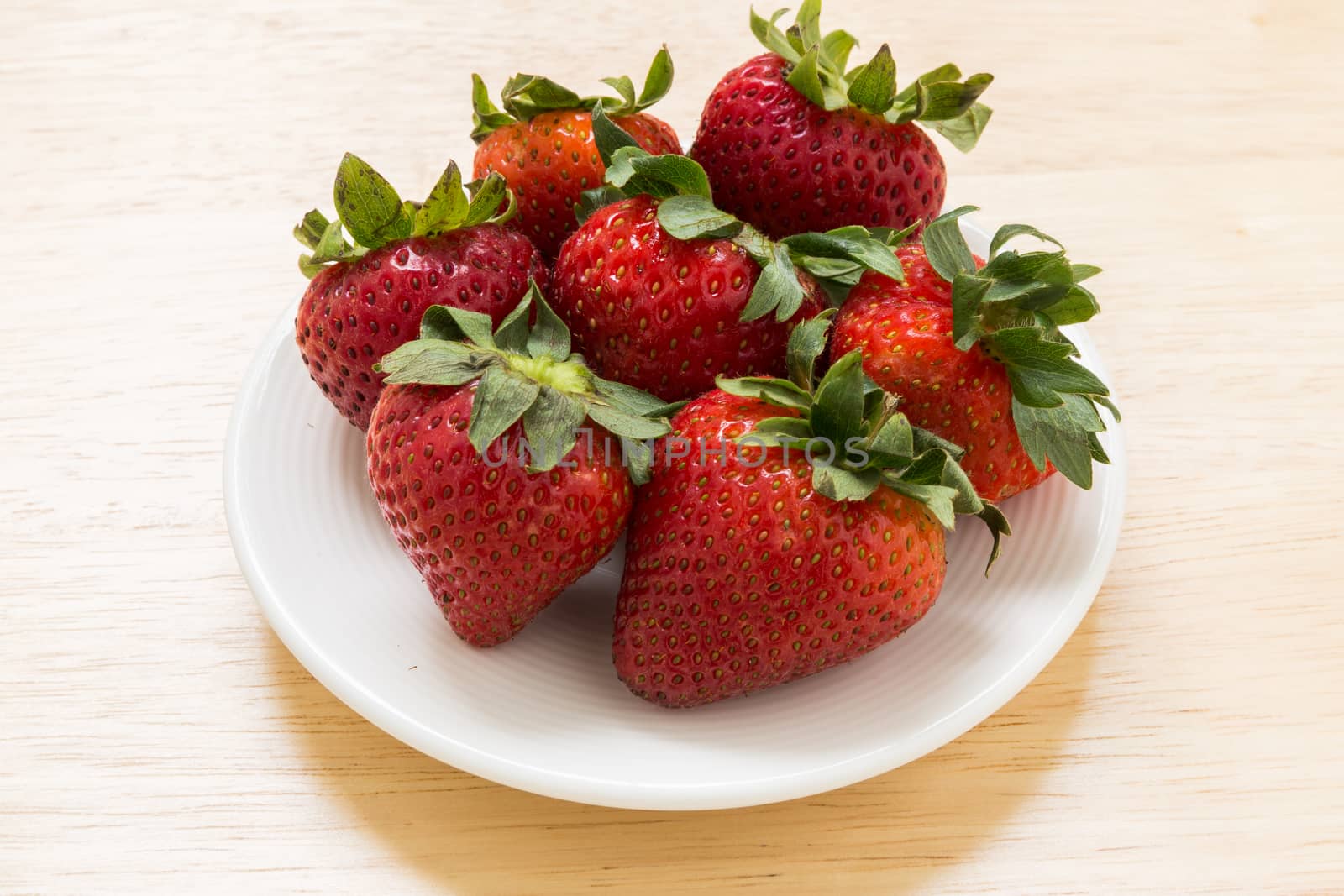 Strawberry in white plate on wooden background