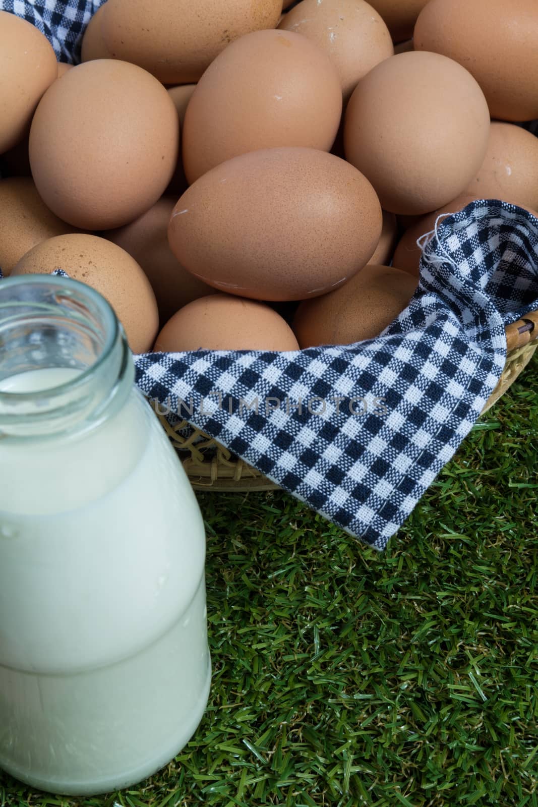 Basket contains group of chicken eggs put on grass.