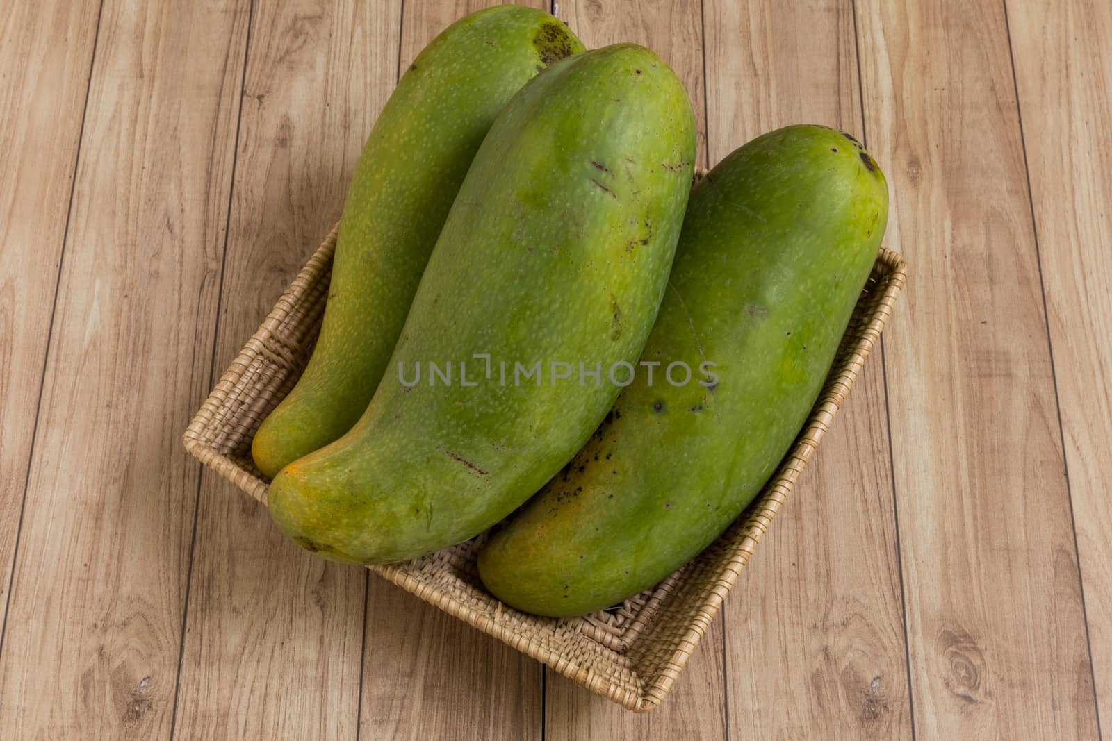 Mangoes from Thailand put in a basket on wood background.