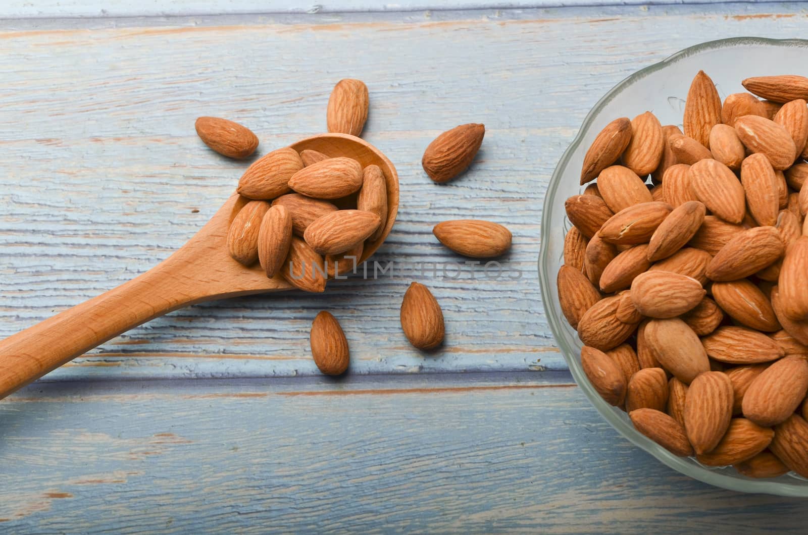 Almond nuts in a glass bowl on a wooden background. Selective focus.