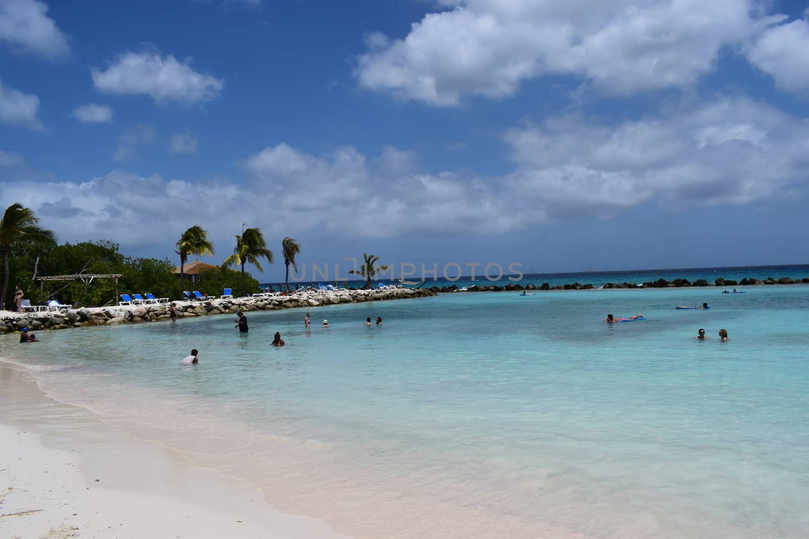 Aruba, Renaissance Island, Caribbean Sea. Sunny beach with white sand, coconut palm trees and turquoise sea. Summer vacation, tropical beach and pink flamingos