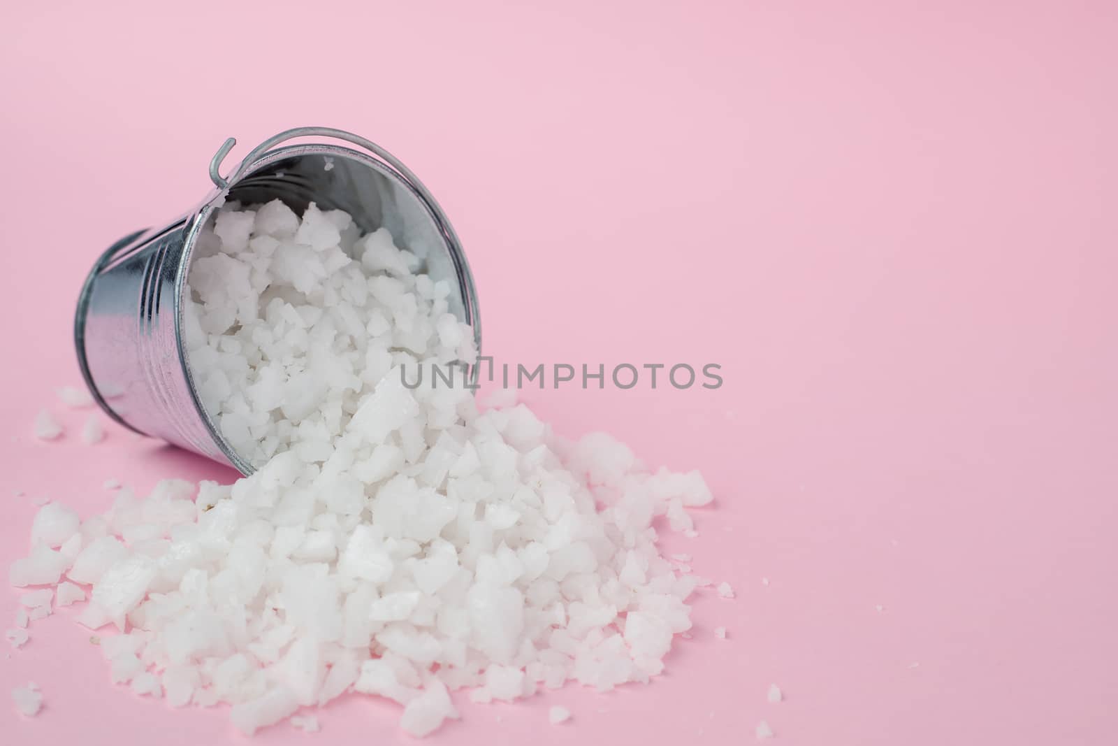 Sea salt in a tin bucket on pink background for seasoning or preserving food
