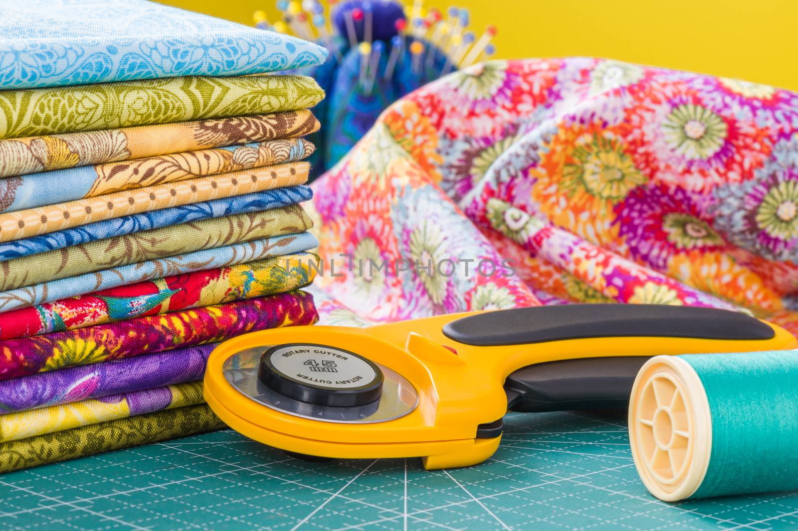 Rotary cutter and spool of thread on a background fabric