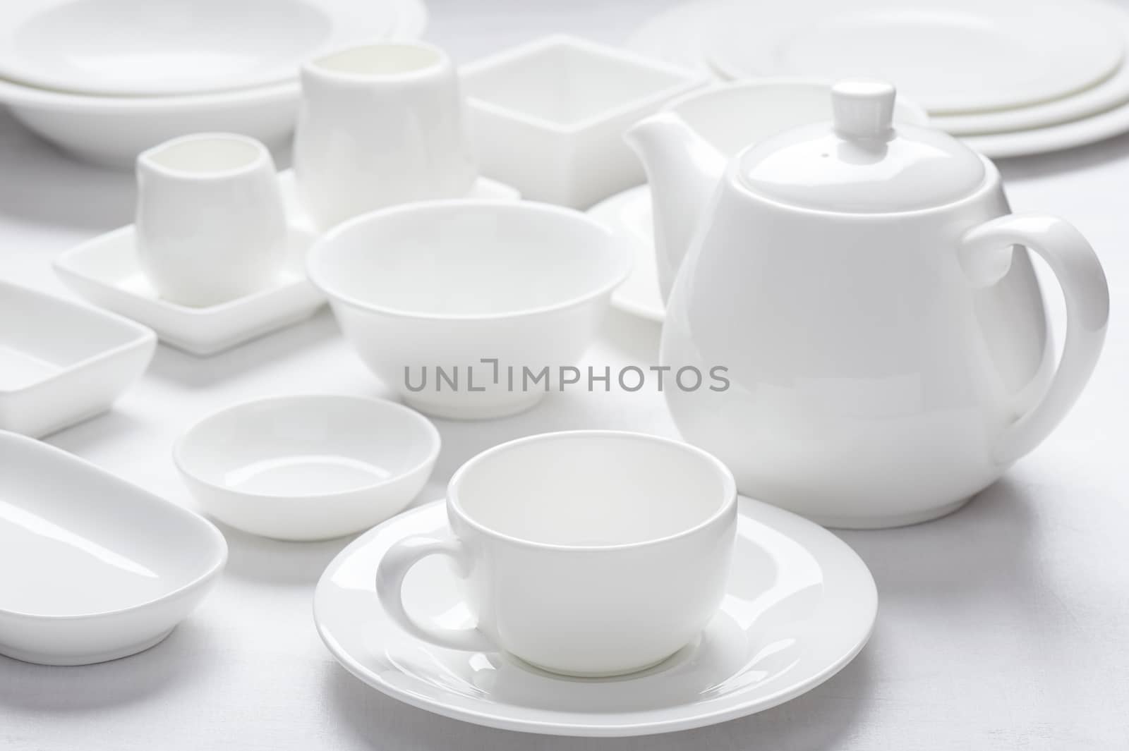 Set white dishes on white wooden surface