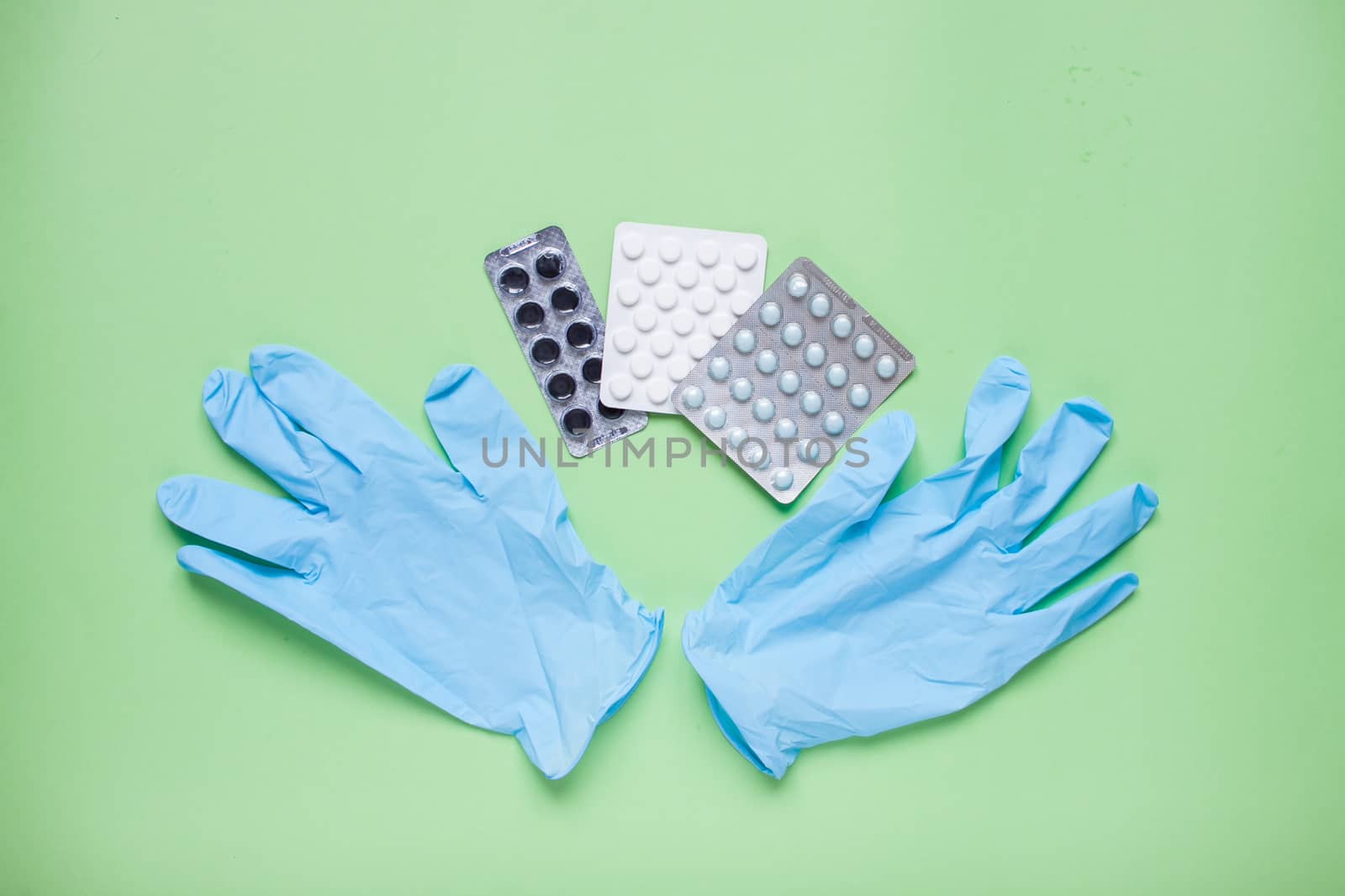 Blisters with pills and rubber protective gloves. Medicine. Layout. Green background