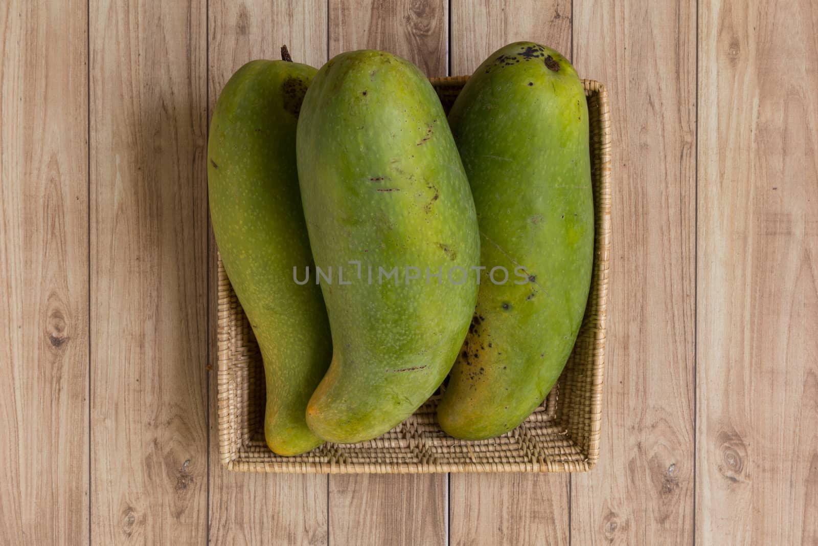 Mangoes from Thailand put in a basket on wood background.
