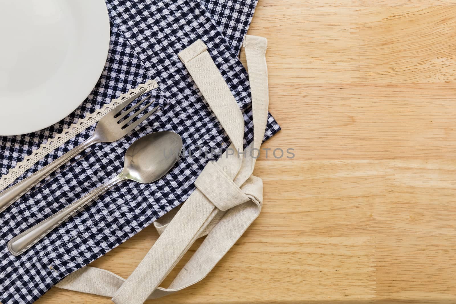 Empty plate with spoon and fork on table background.