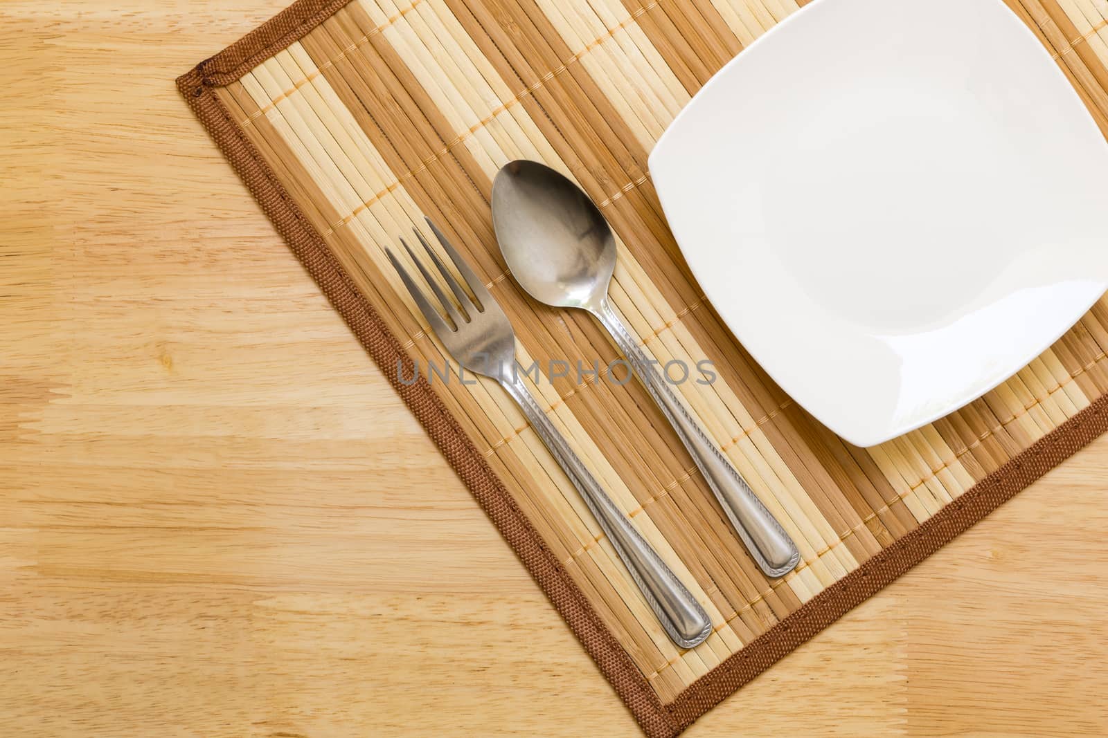 Empty plate with spoon and fork on table background.