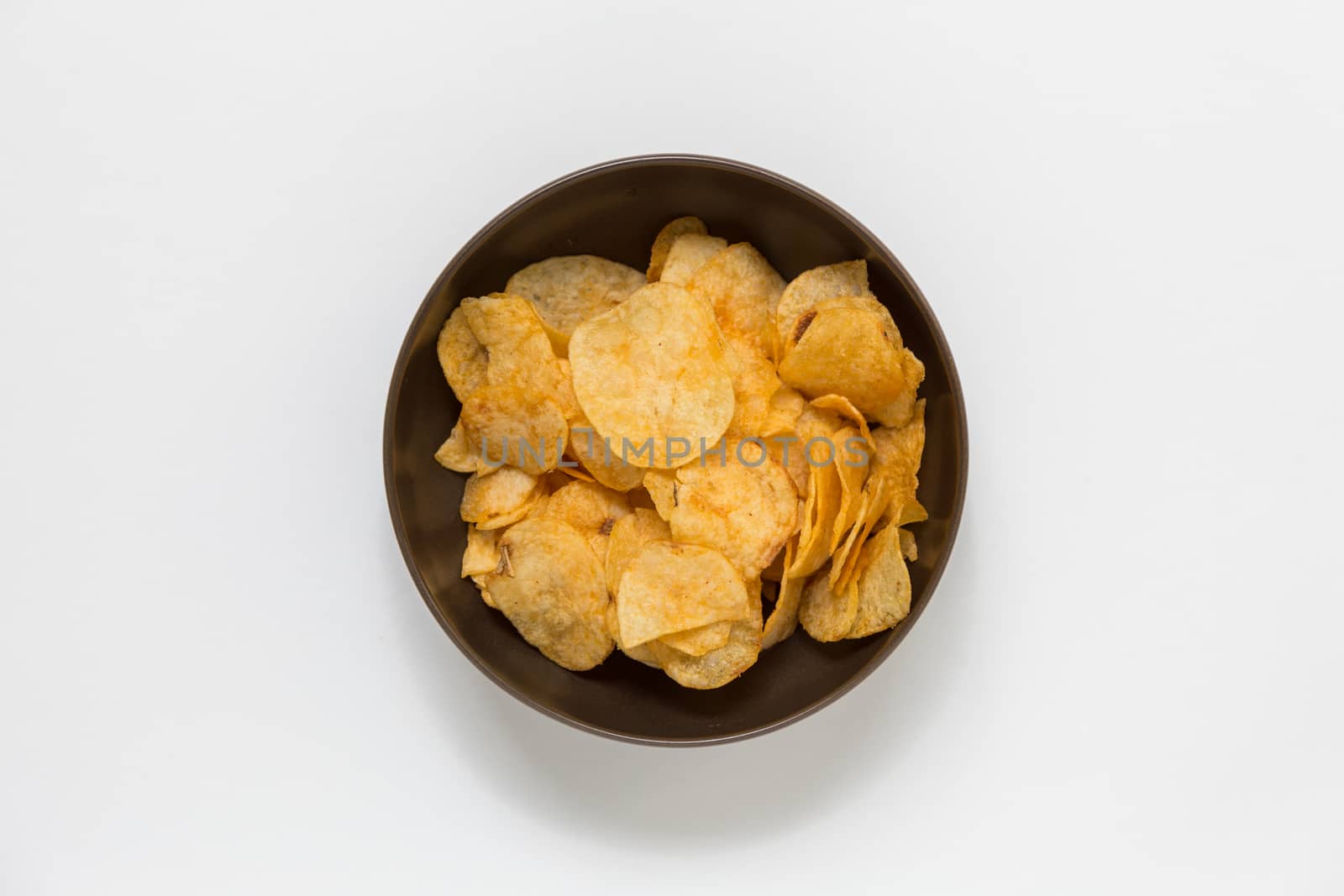 Crispy potato chips in a big brown bowl on white background.