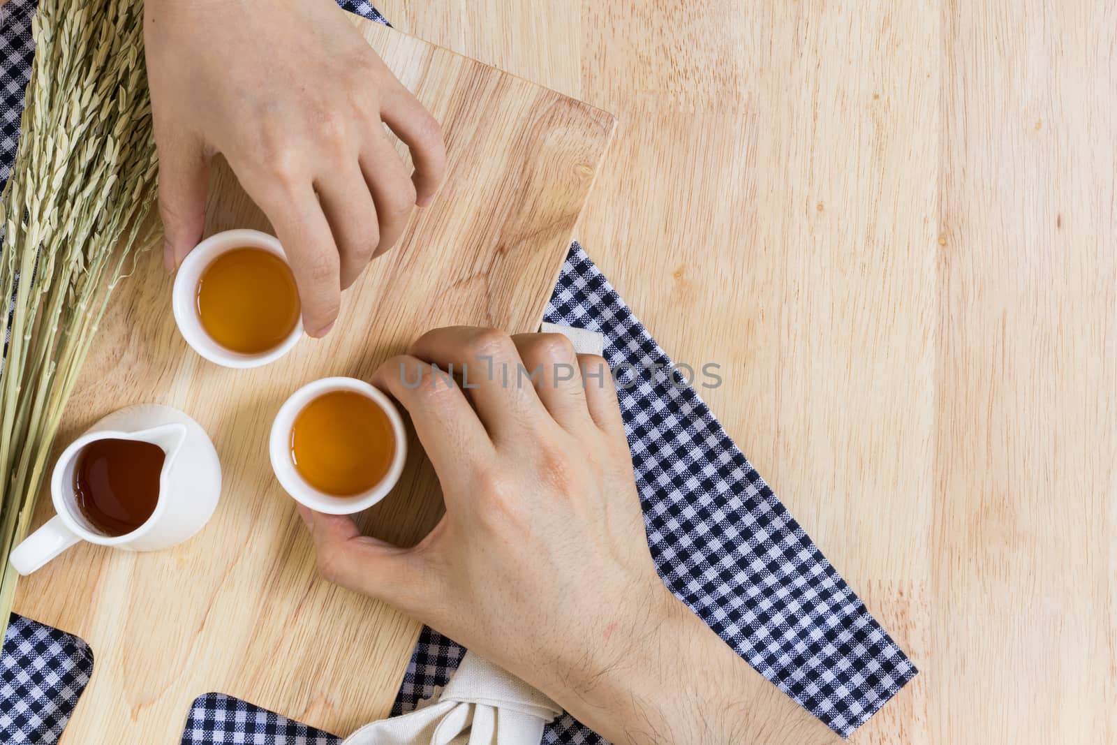 Hands Taking Tea Cups on Wood Texture Background