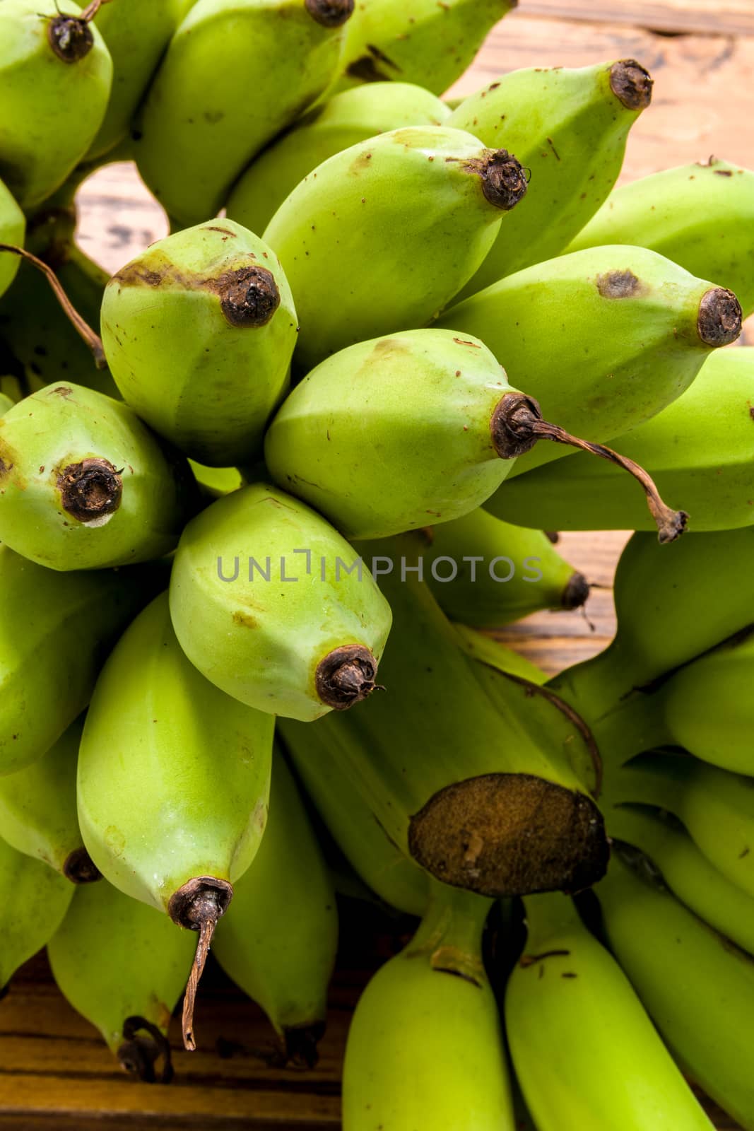 Bunch of unripe banana on wooden background.