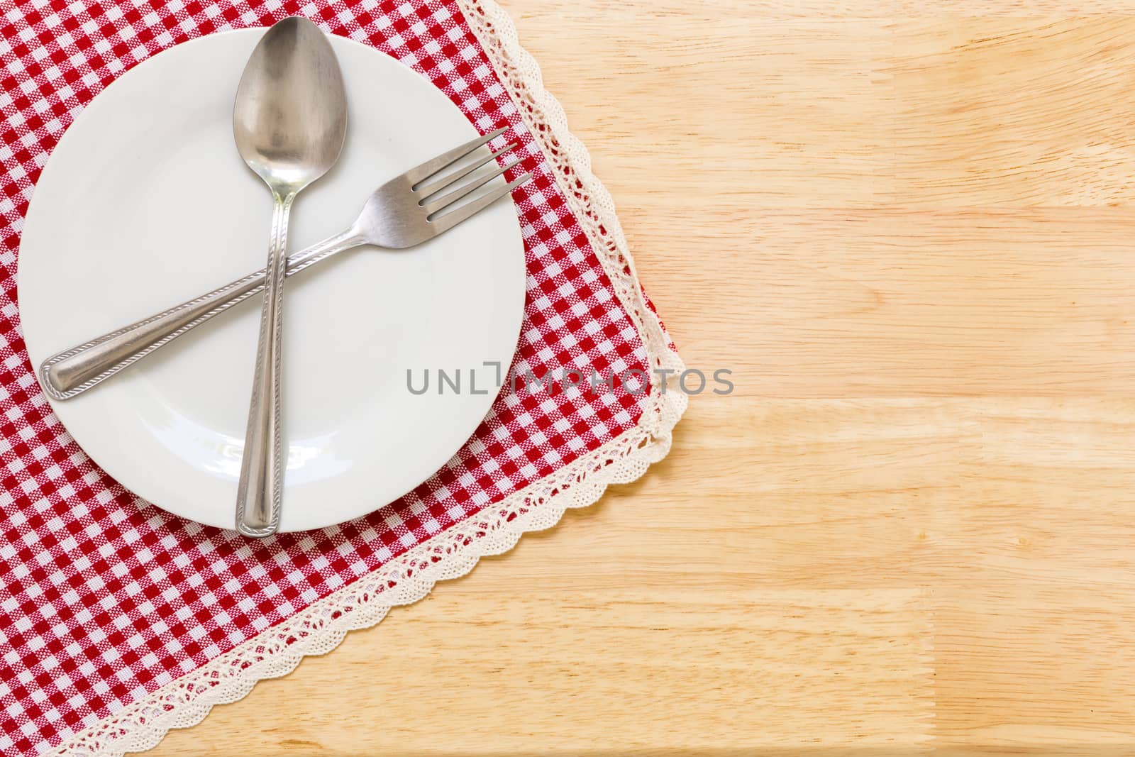 Empty plate with spoon and fork on table background.
