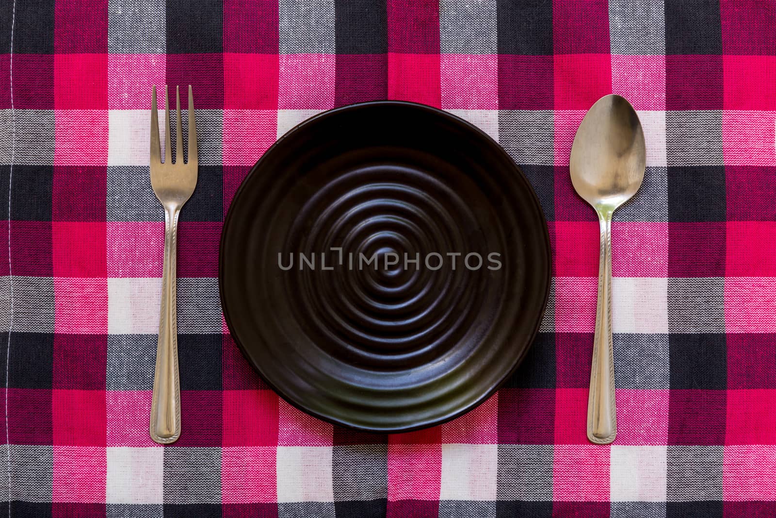 Empty plate with spoon and fork on table background.