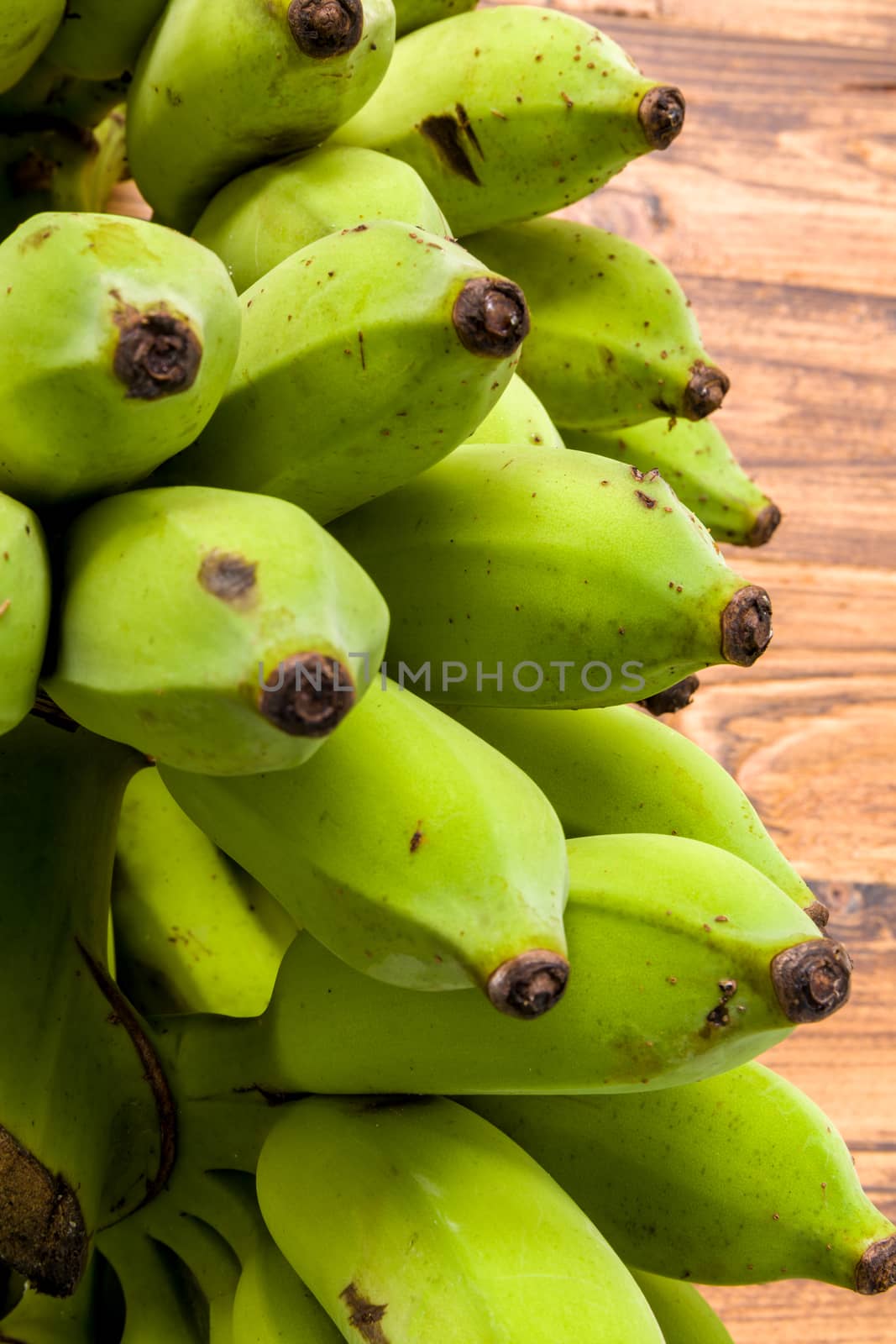 Bunch of unripe banana on wooden background.