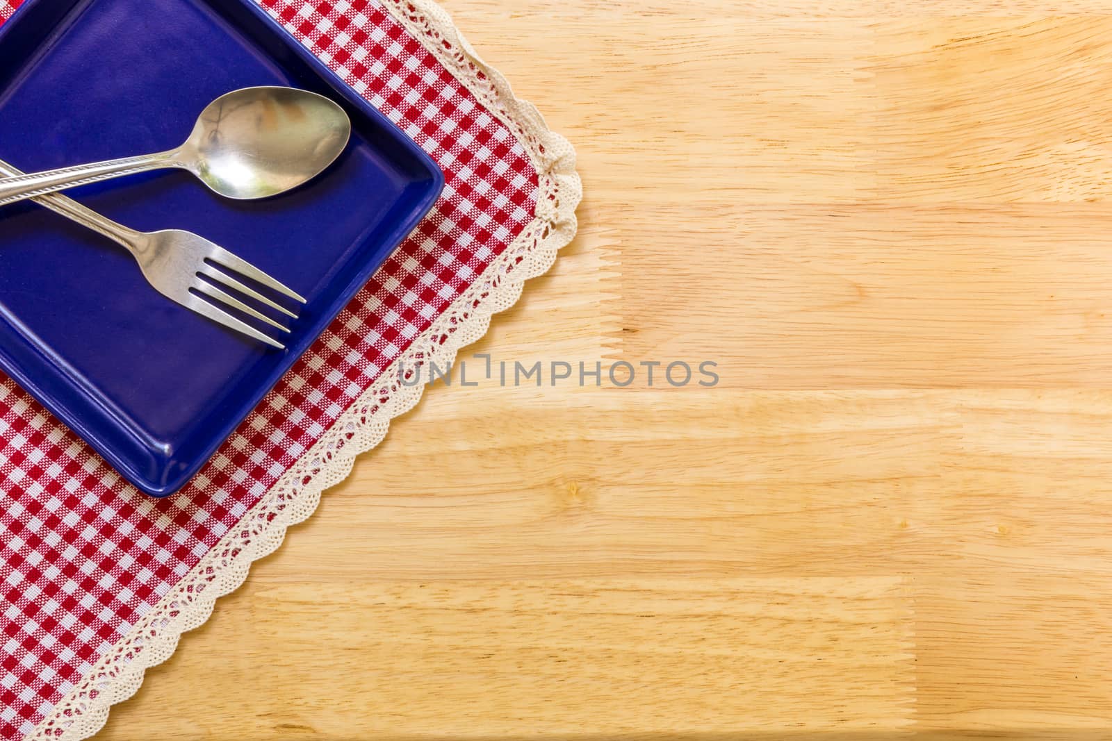 Empty plate with spoon and fork on table background.