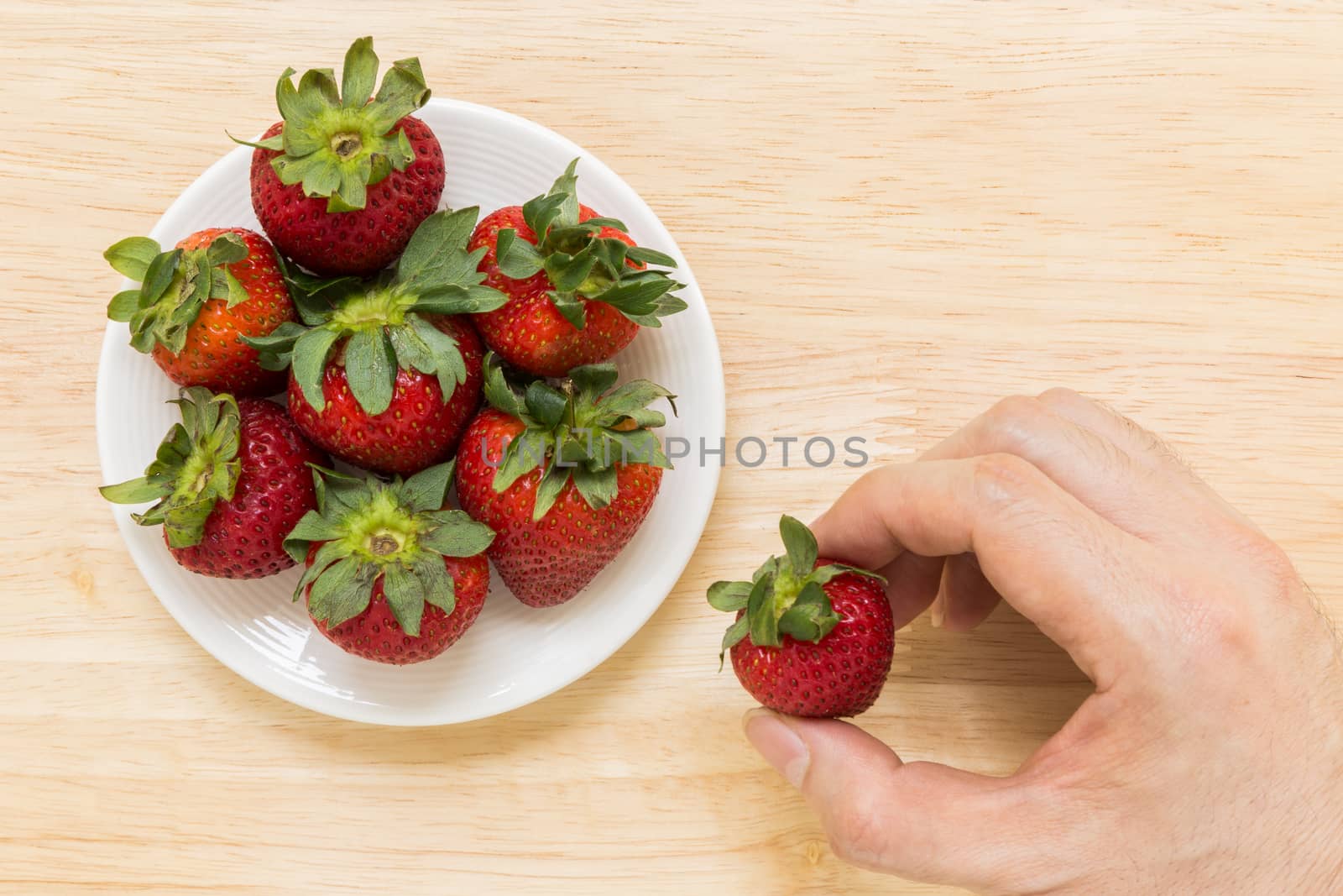 Strawberry in white plate on wooden background