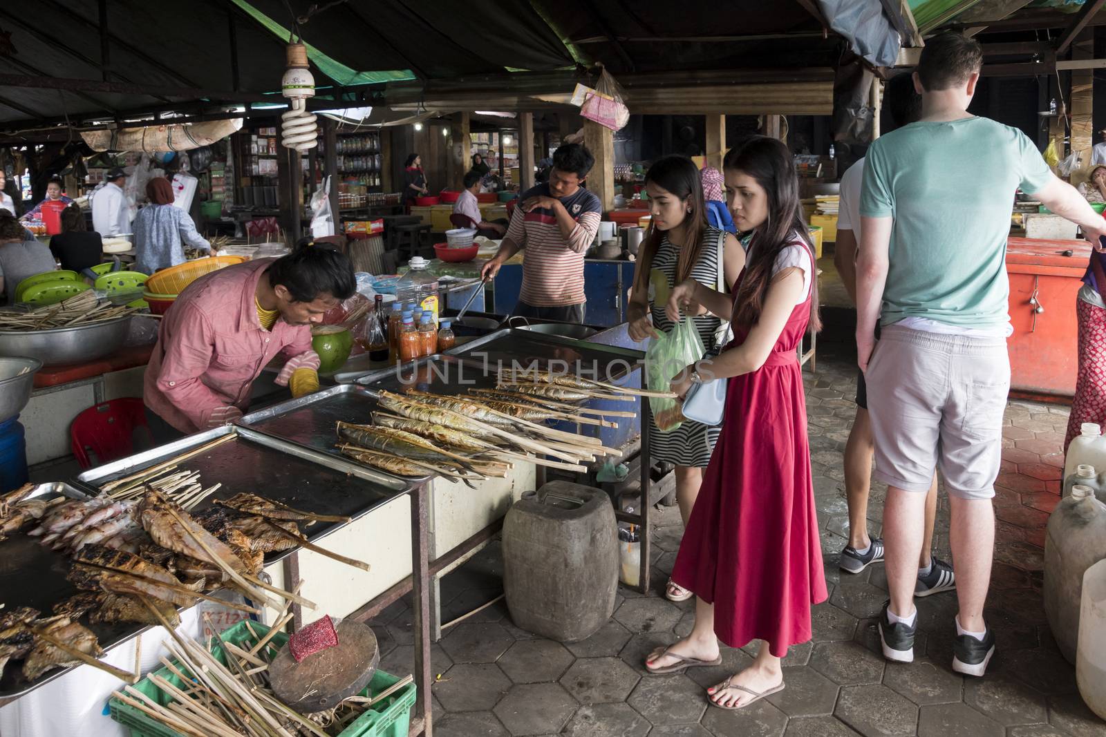 Krong Kaeb, Kep Province, Cambodia, 30 March 2018. Girls buying seafood skewers at the Crab Market