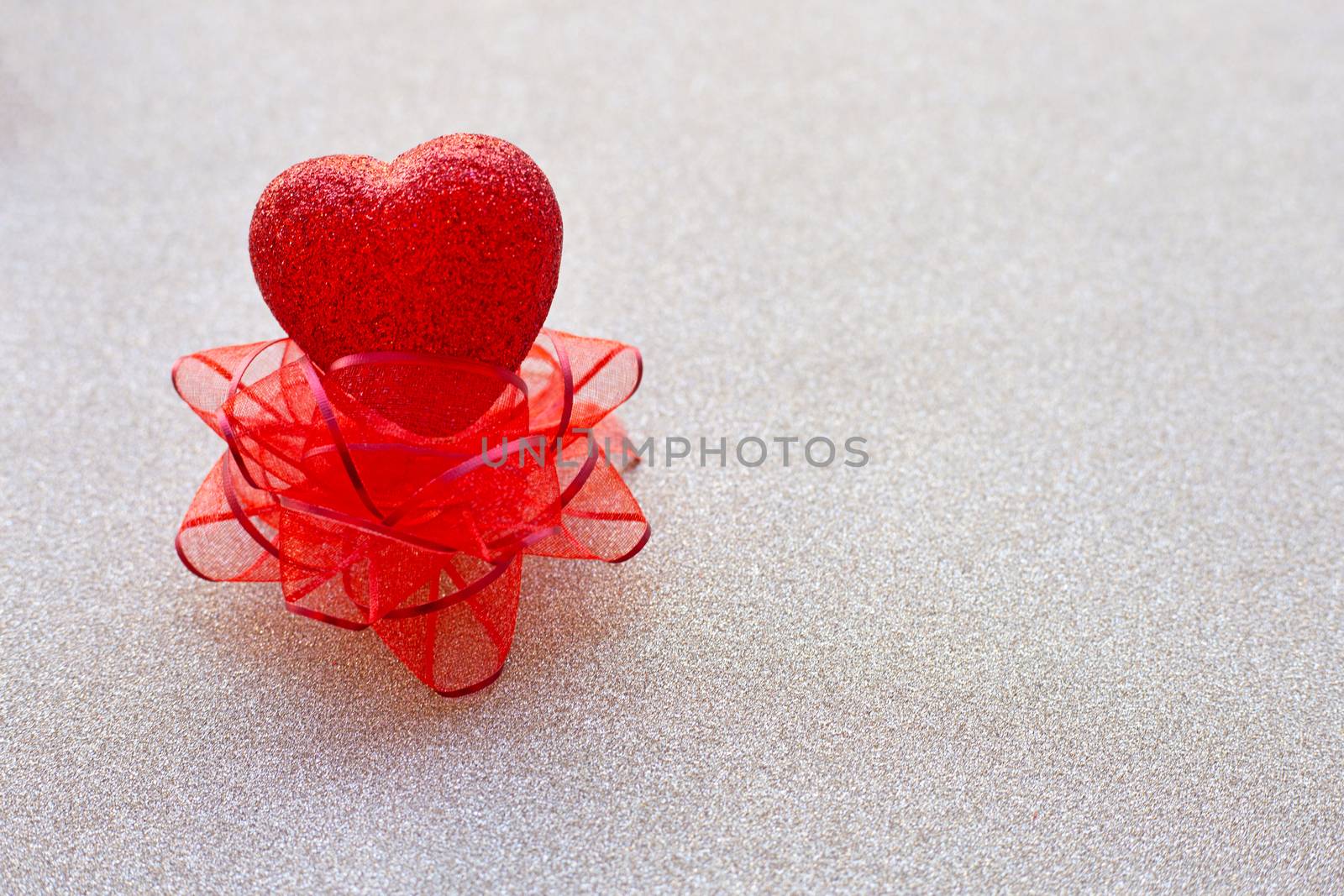 The red heart shapes on red bow on  silver glitter paper background  in love concept for valentines day. Copy space