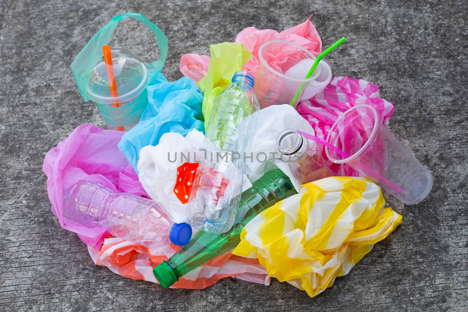 Colorful plastic waste, bags, cups, bottles, straws on cement floor background