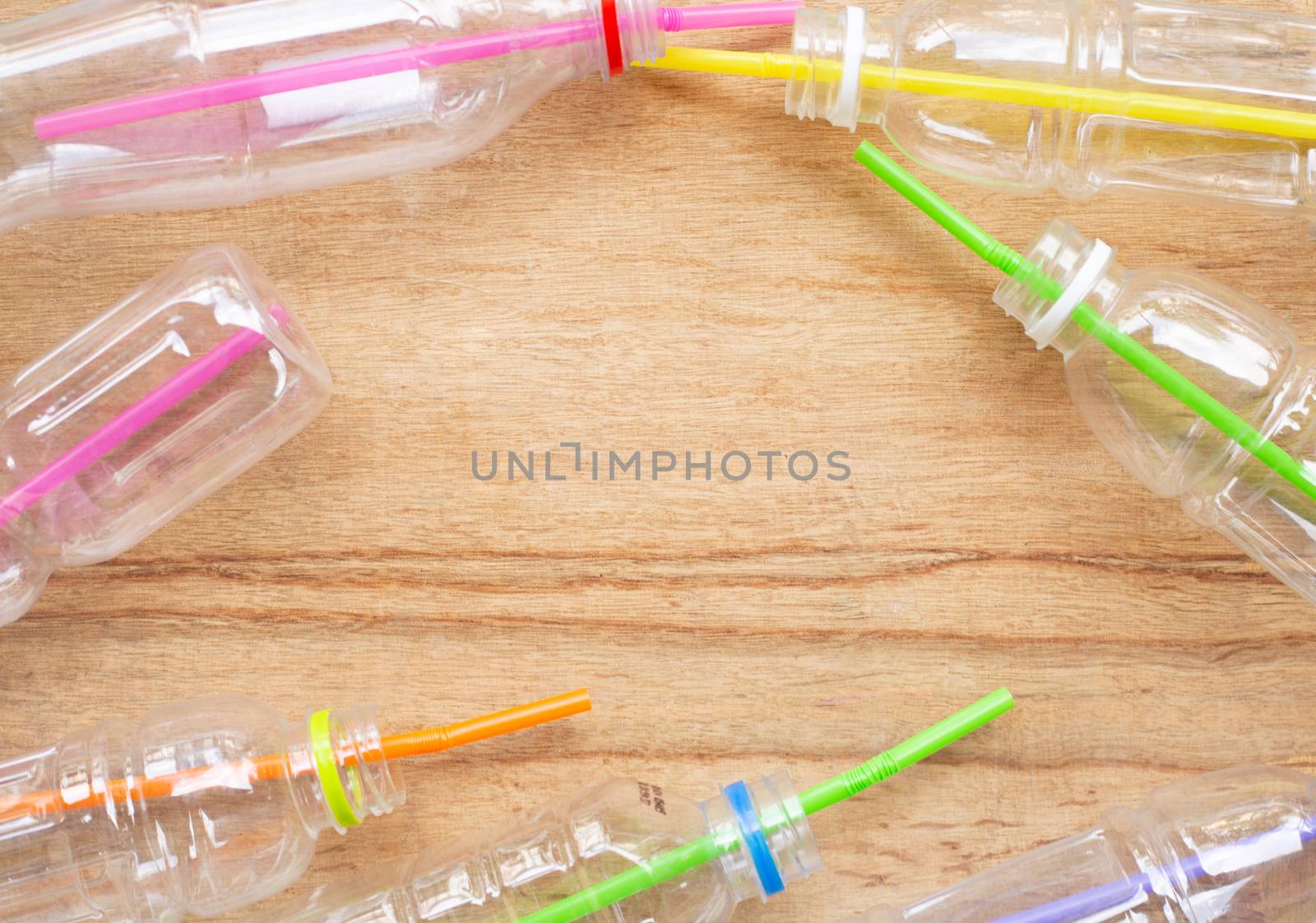 Plastic waste, Plastic bottles with straws on wooden background.