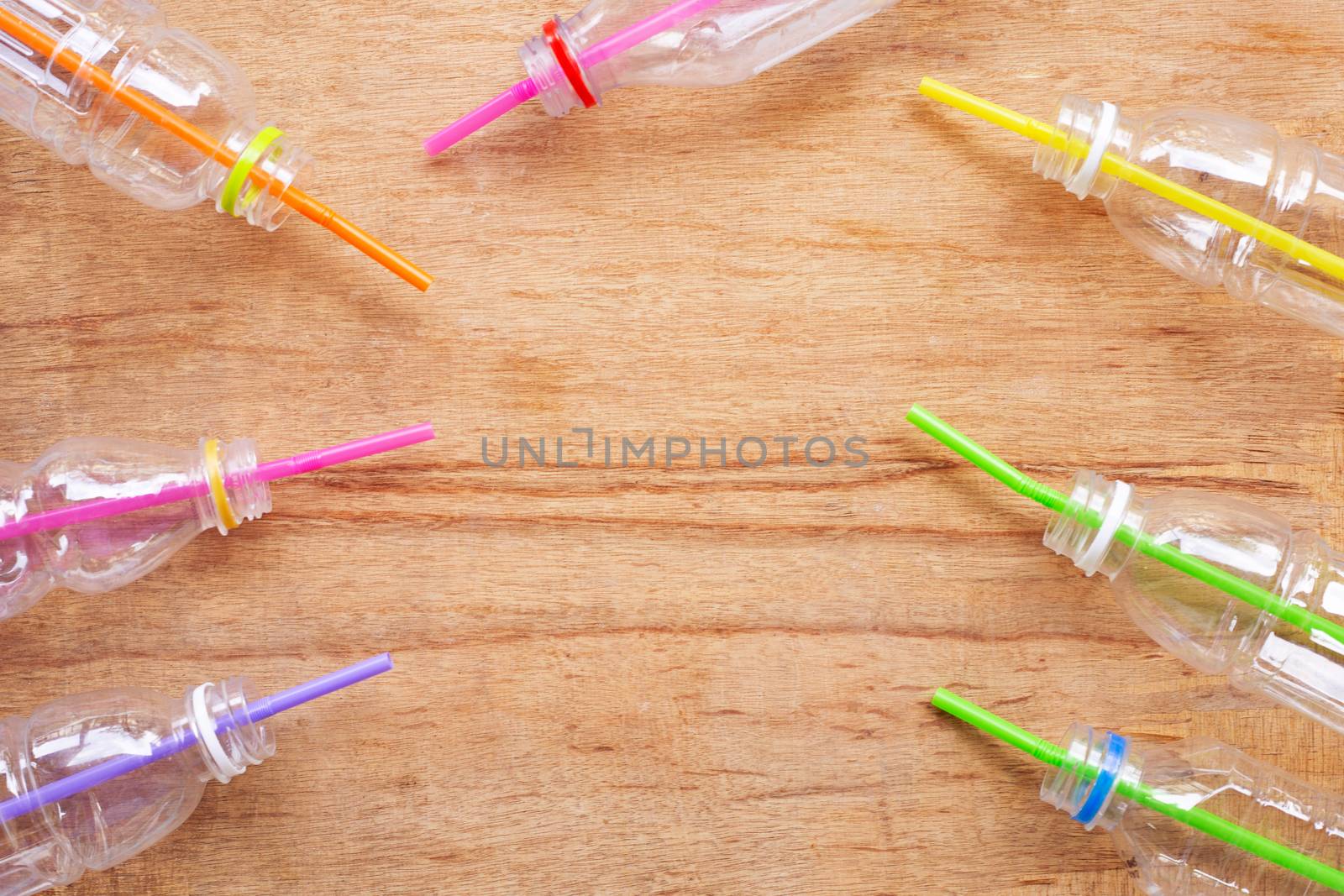 Plastic waste, Plastic bottles with straws on wooden background.