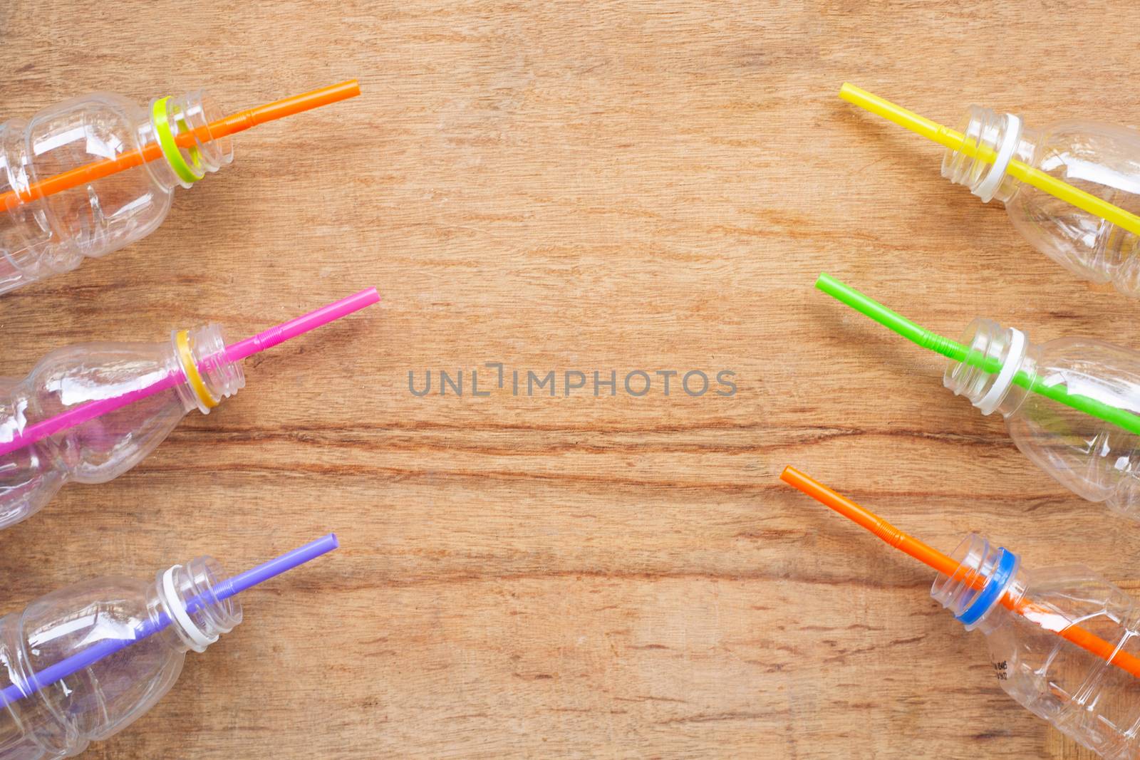 Plastic waste, Plastic bottles with straws on wooden background.