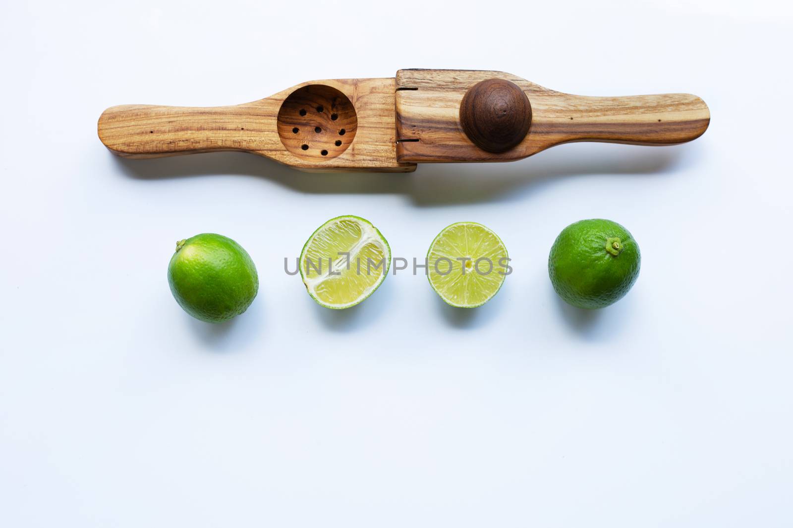 Limes with wooden lime squeezer on white background