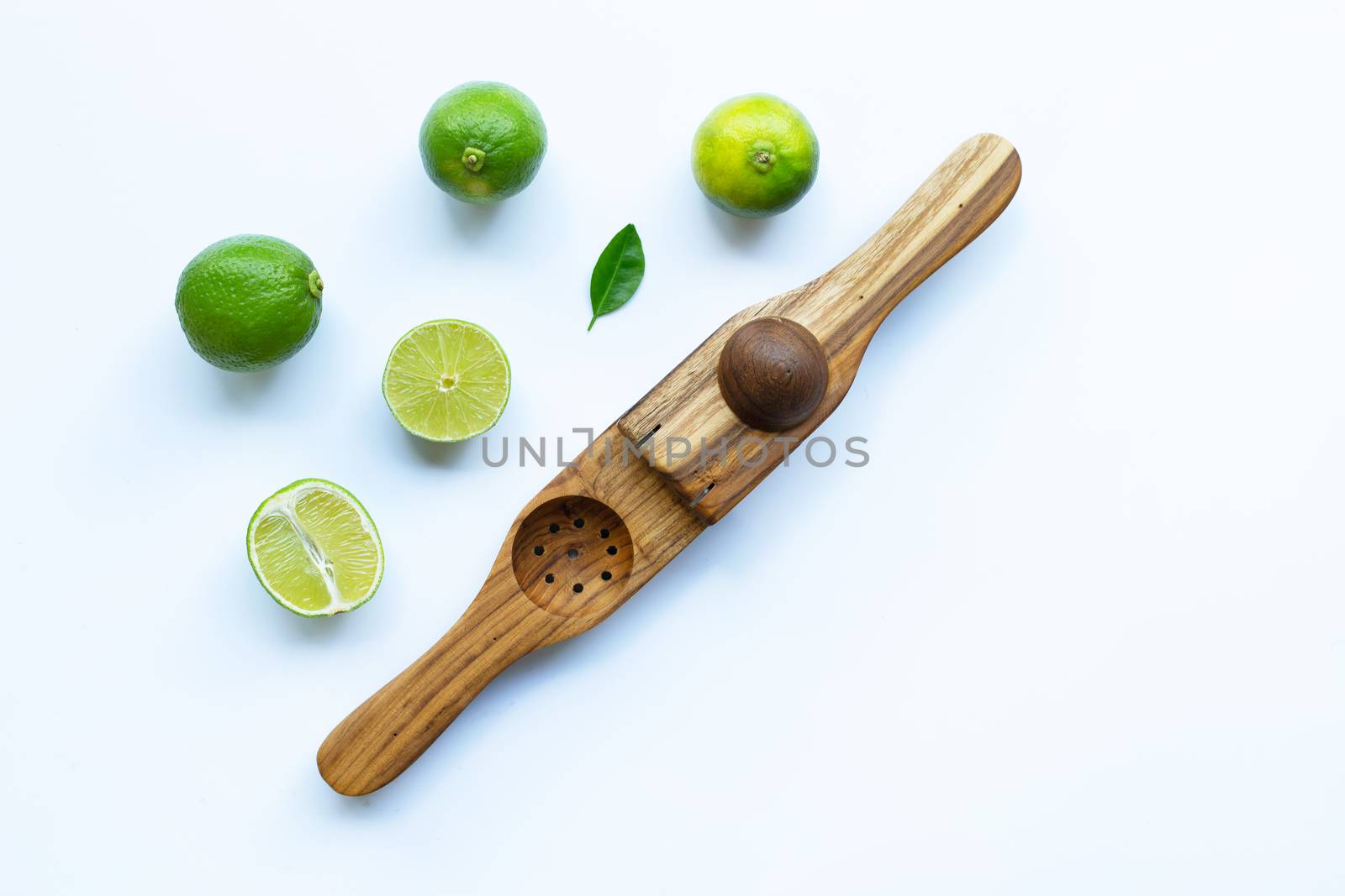 Limes with wooden lime squeezer on white background