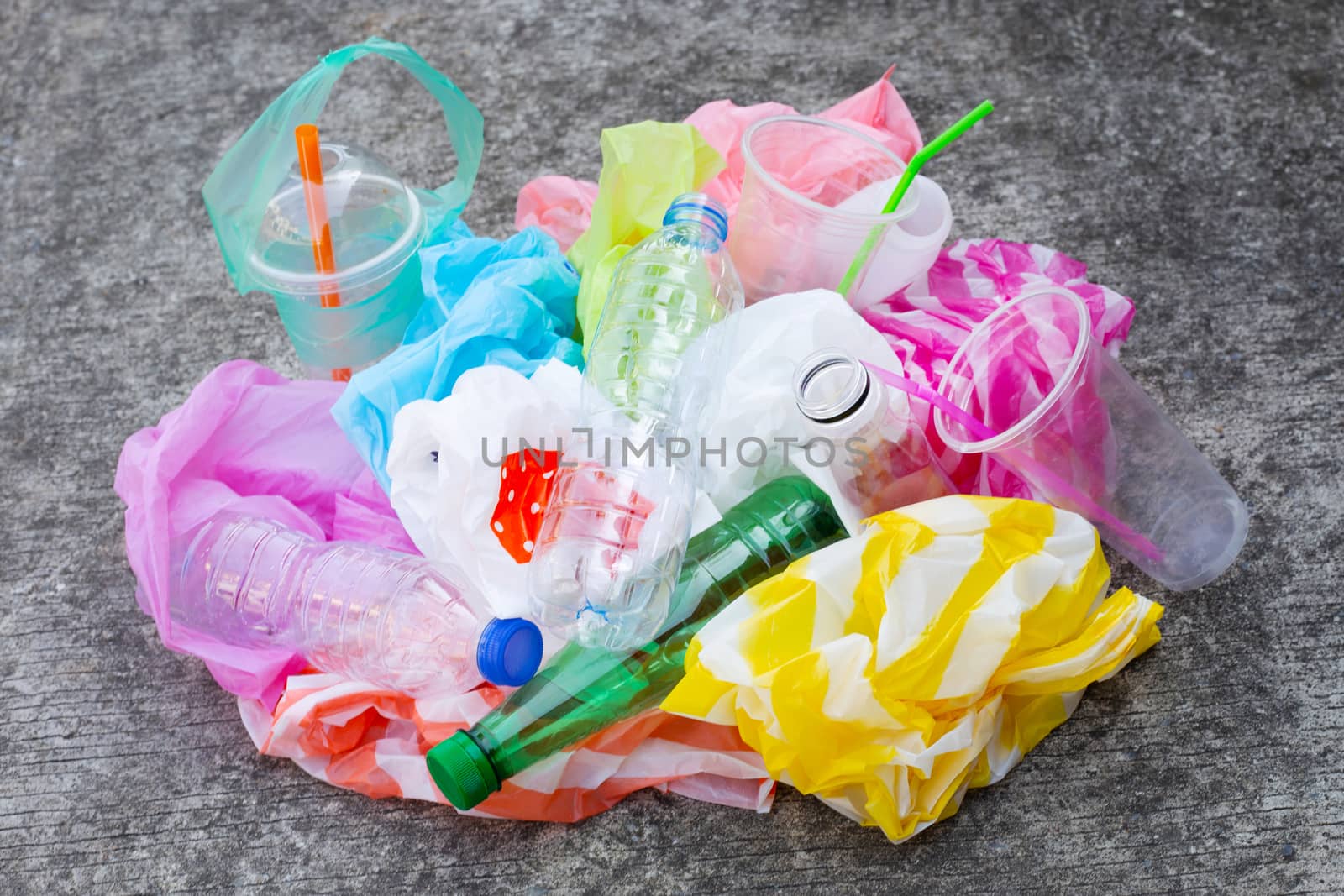 Colorful plastic waste, bags, cups, bottles, straws on cement floor background