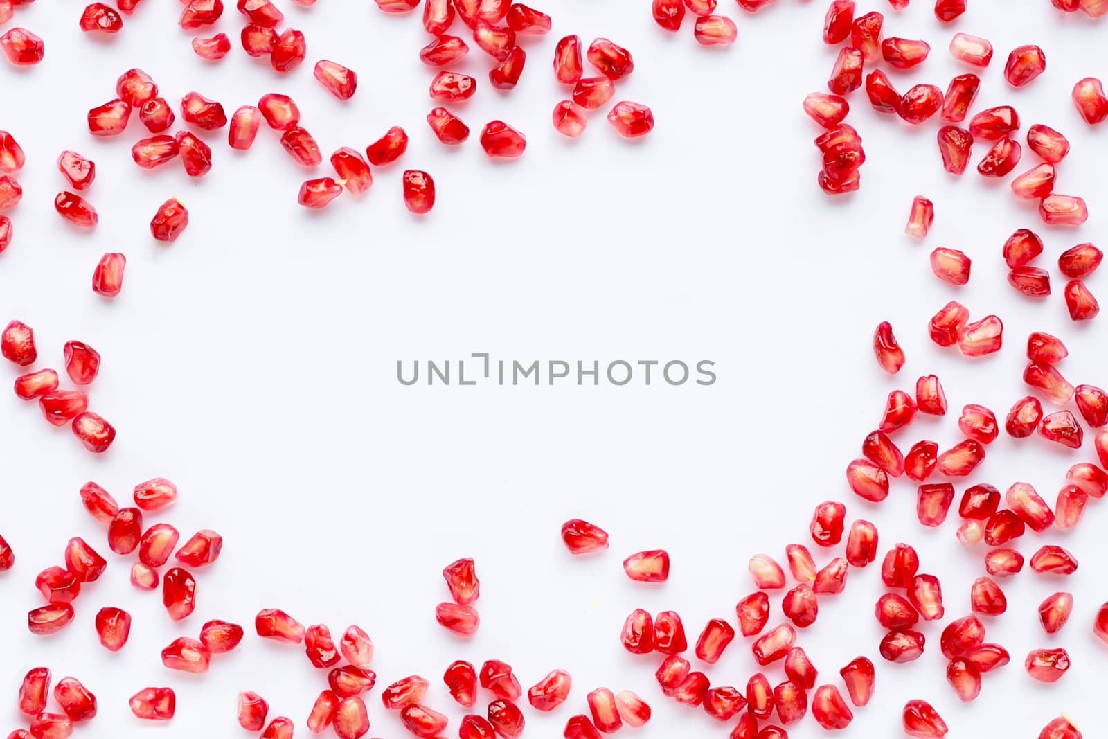 Frame made of pomegranate seeds isolated on white background. Copy space