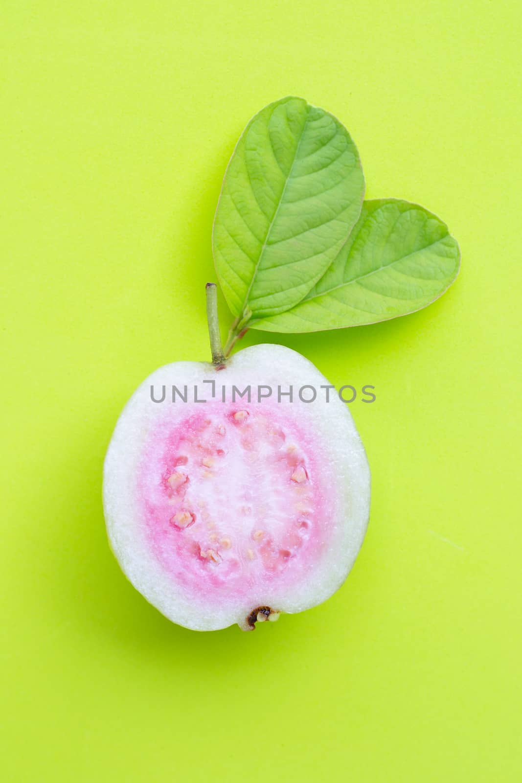 Top view of fresh ripe guava and slices with leaves on green background.