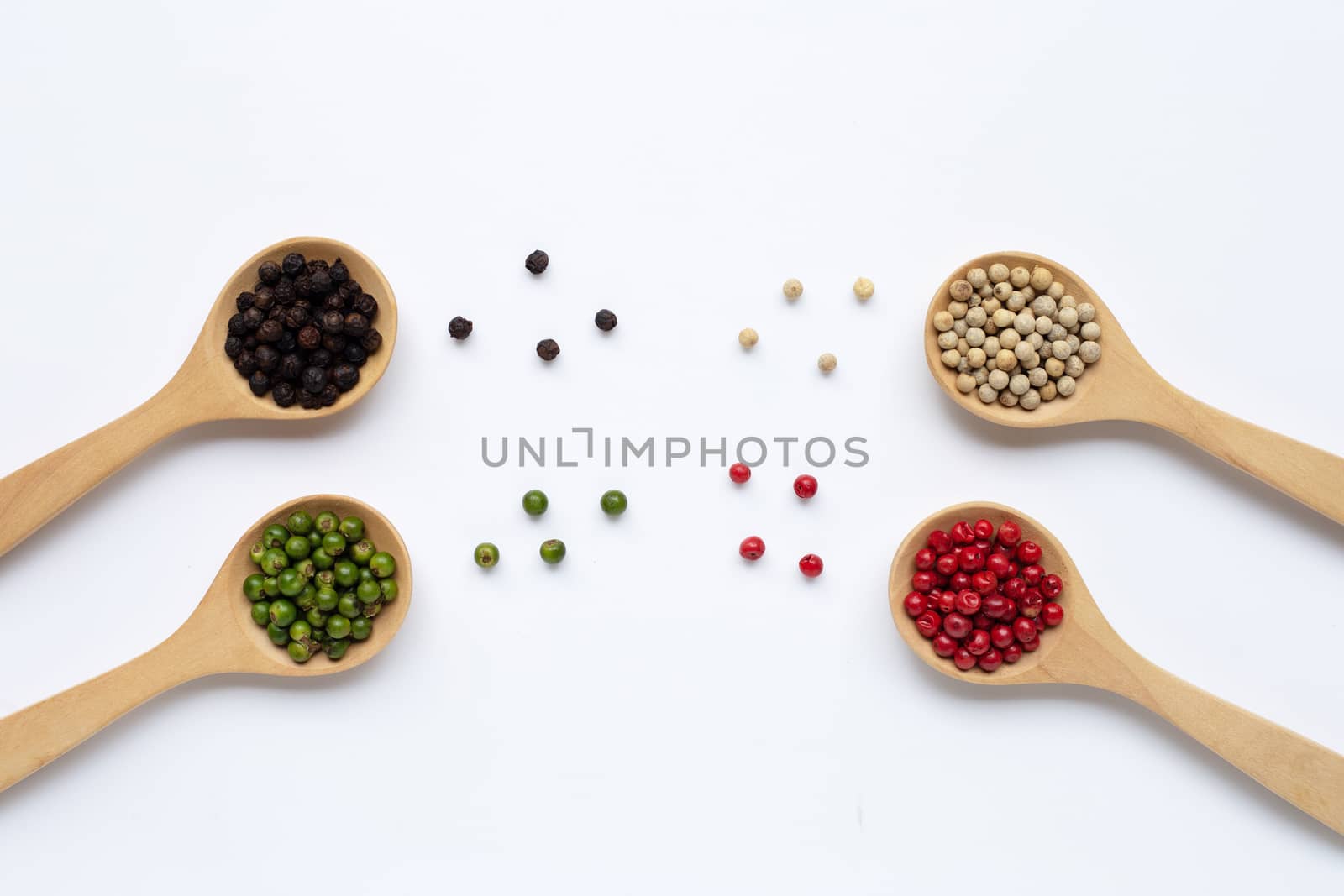 Green, red, white and black peppercorns with wooden spoon on white background.