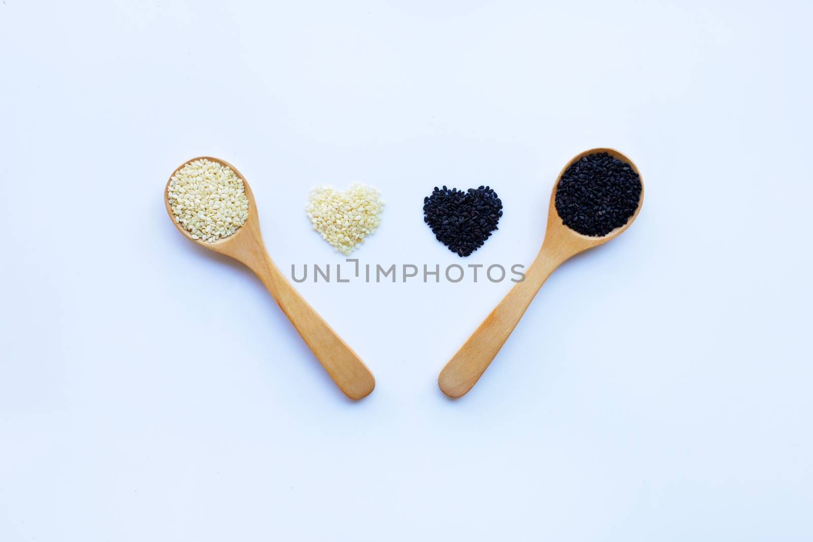 Black and white sesame seeds on wooden spoon, white background. 