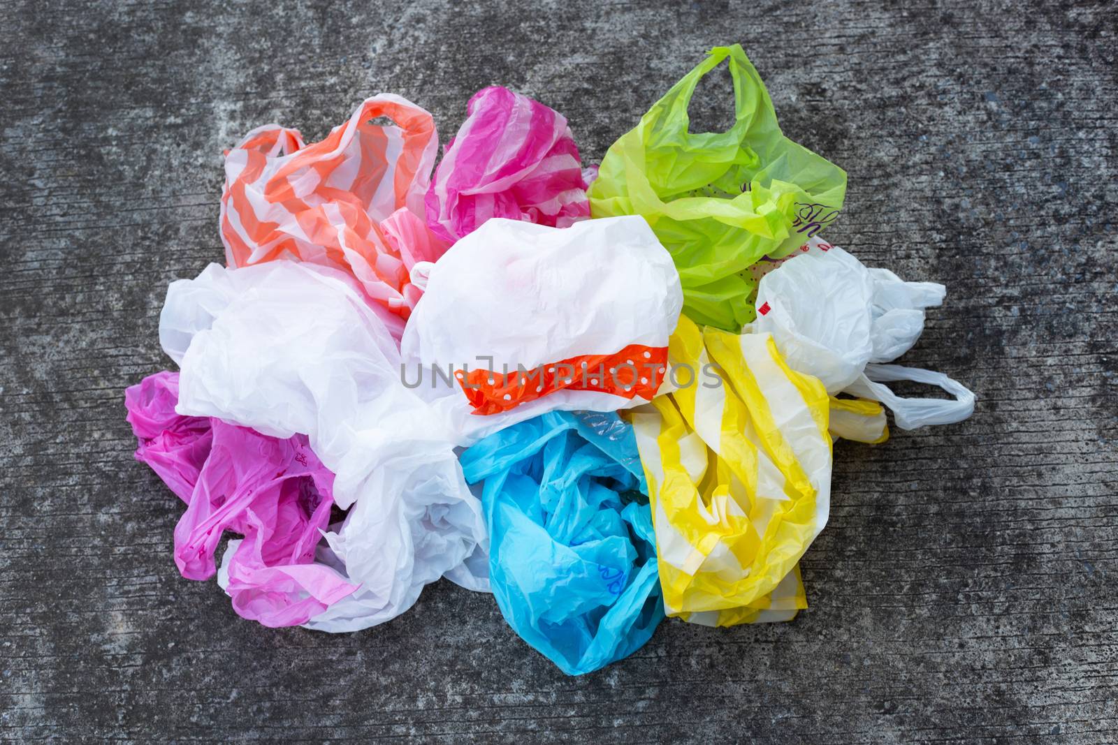 Colorful plastic bags on dirty cement floor background.