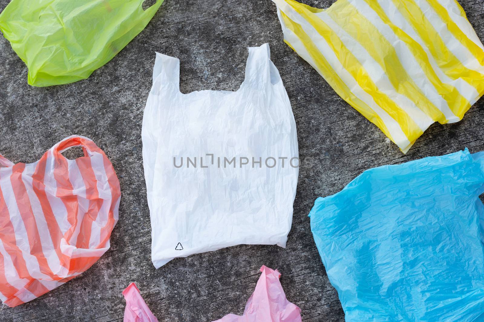 Colorful plastic bags, waste on cement floor background.