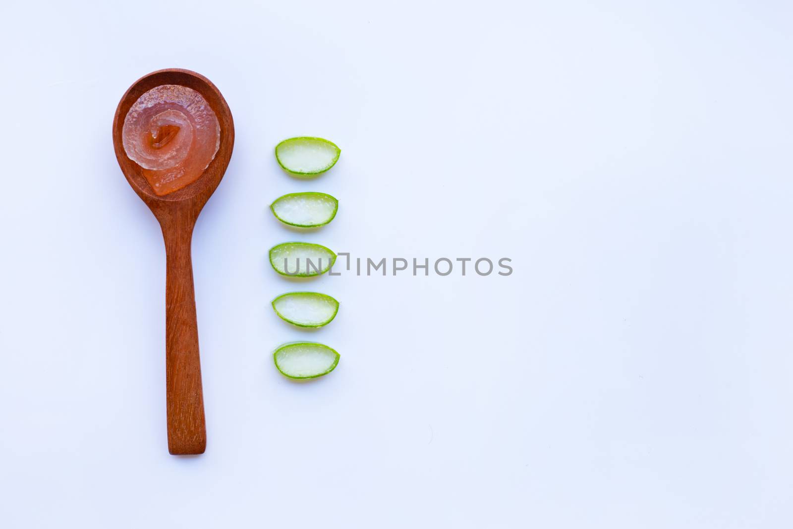 Aloe vera gel on wooden spoon with aloe vera slices on white background. Copy space