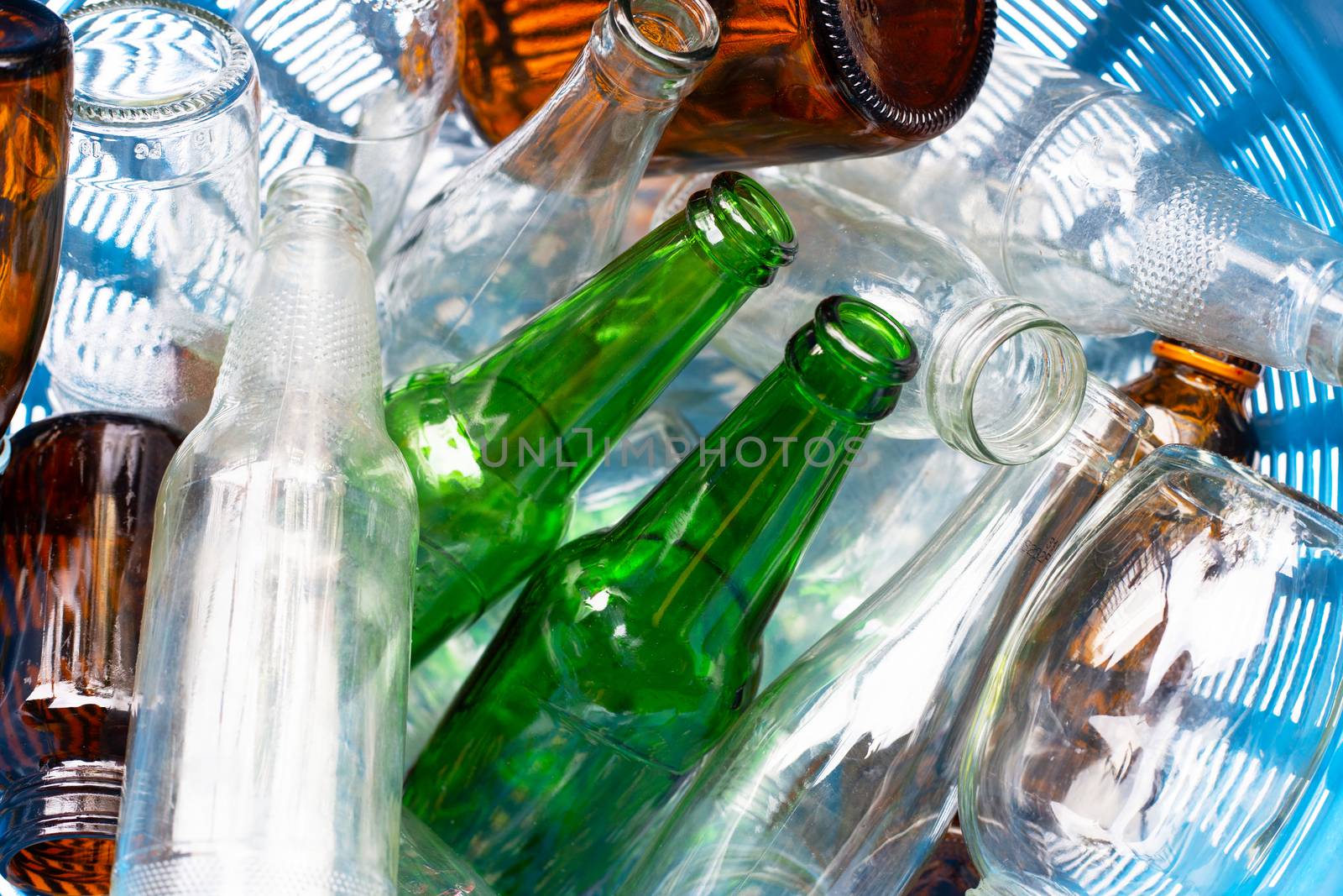 Glass bottles in blue waste basket.