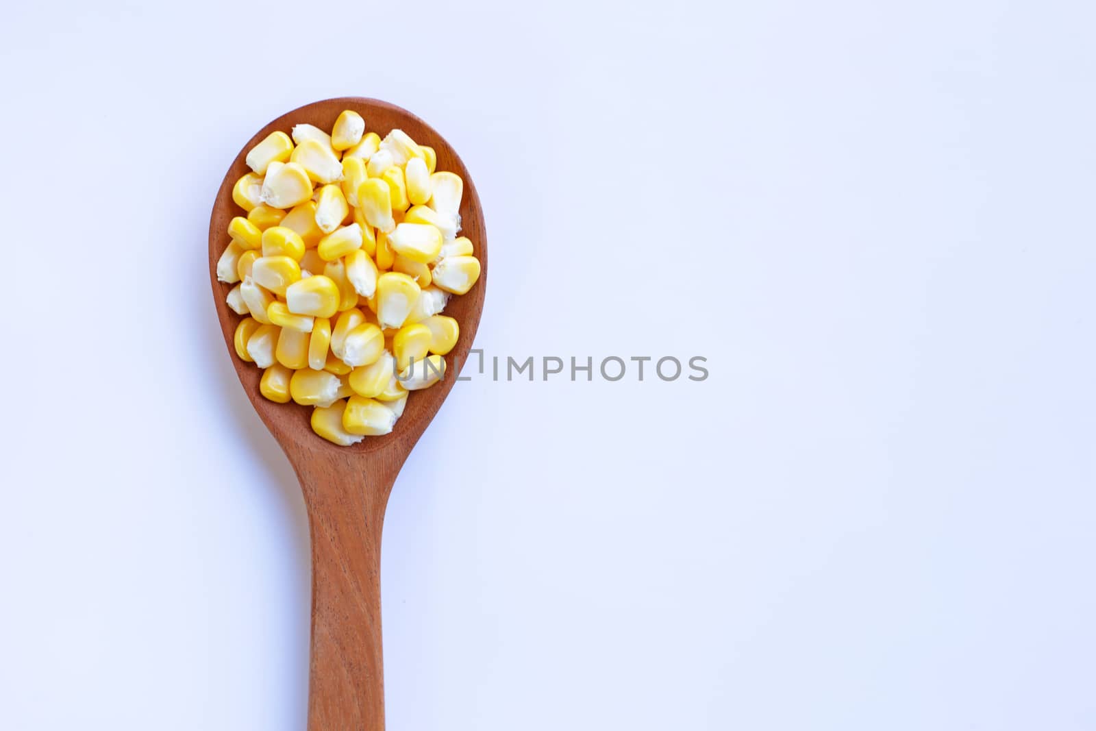 Corn seeds on wooden spoon, white background