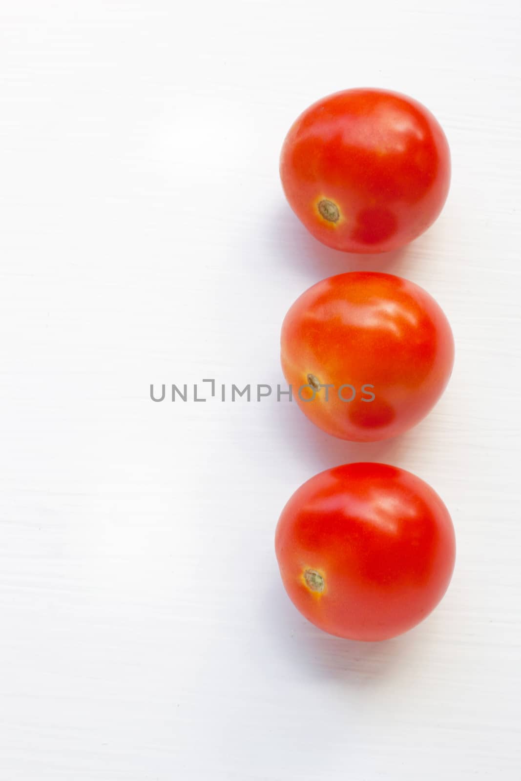 Tomatoes on white wooden background.