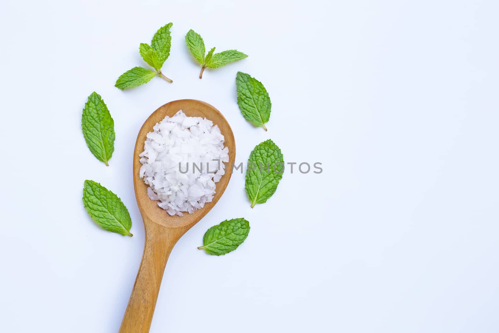 Salt in wooden spoon with fresh mint on white background