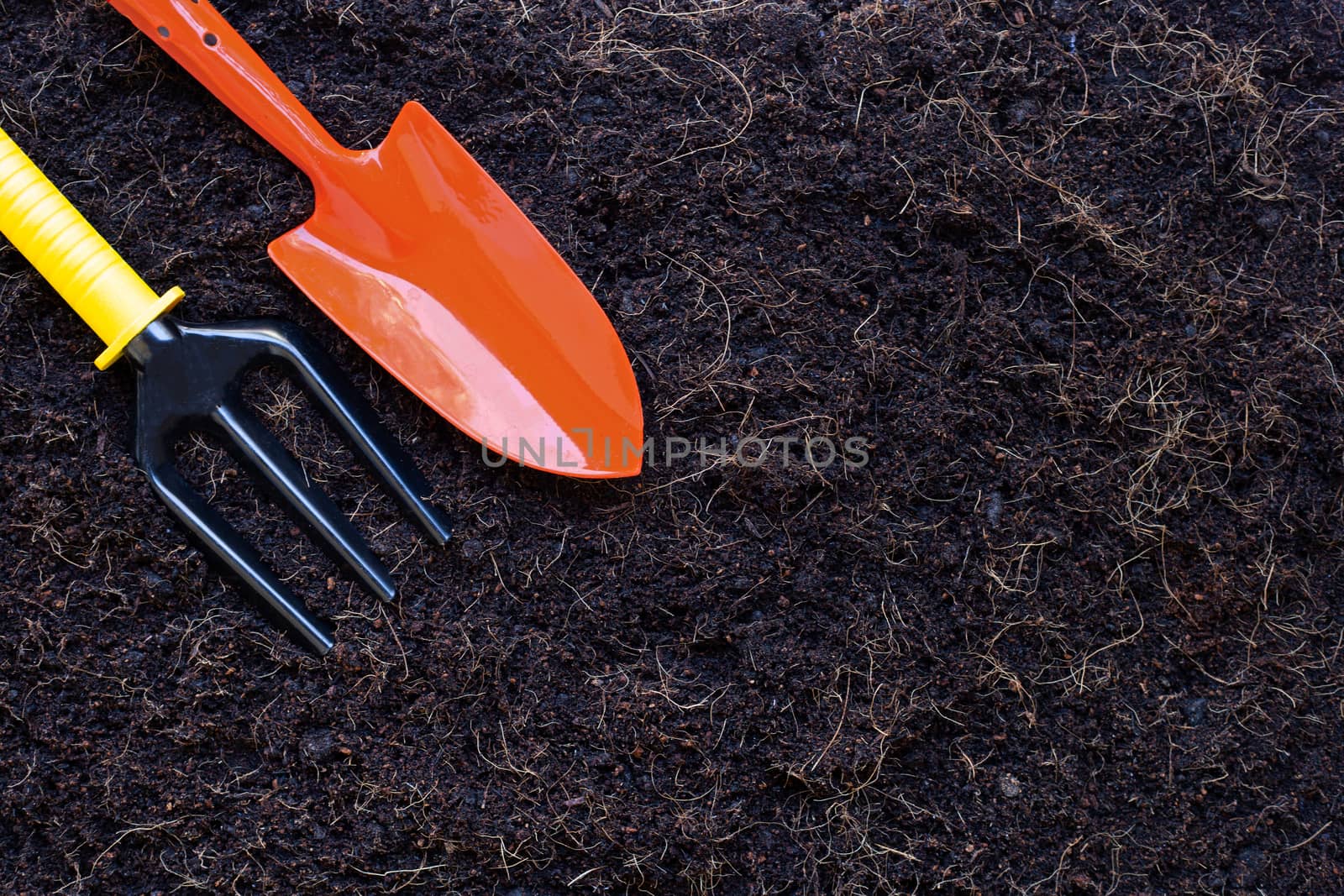 Garden shovel and fork on soil with coconut shell's hair for agriculture.