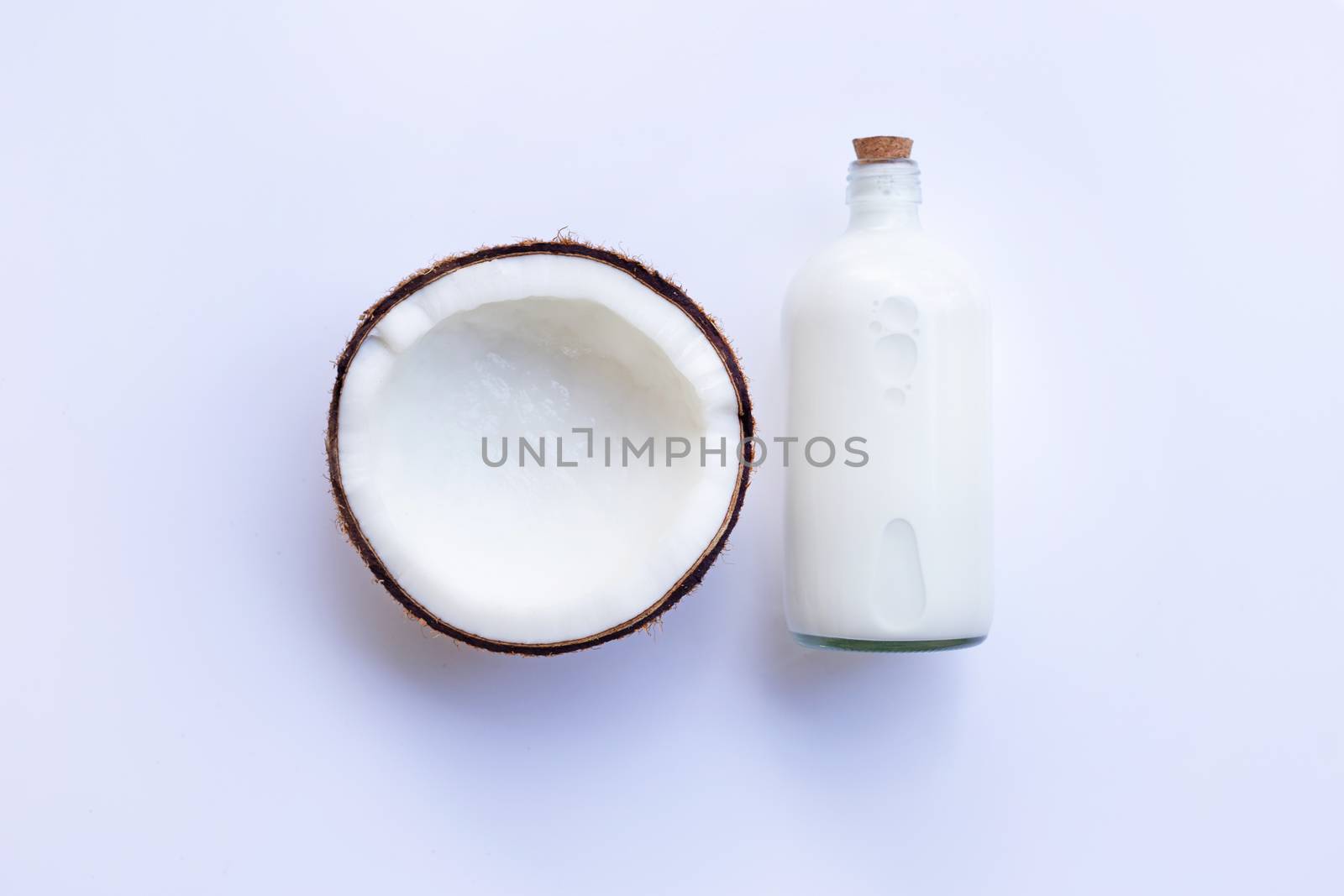 Coconut with bottle of coconut milk on white background.