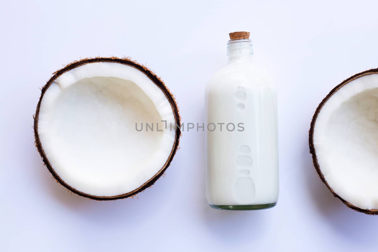 Half Coconut with bottle of coconut milk on white background.