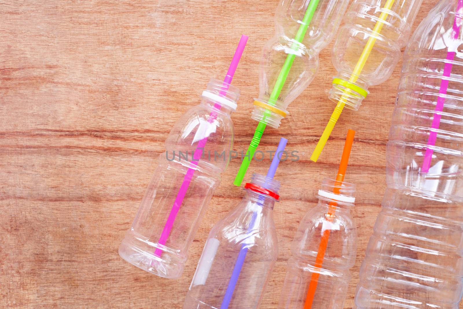 Plastic waste, Plastic bottles with straws on wooden background.