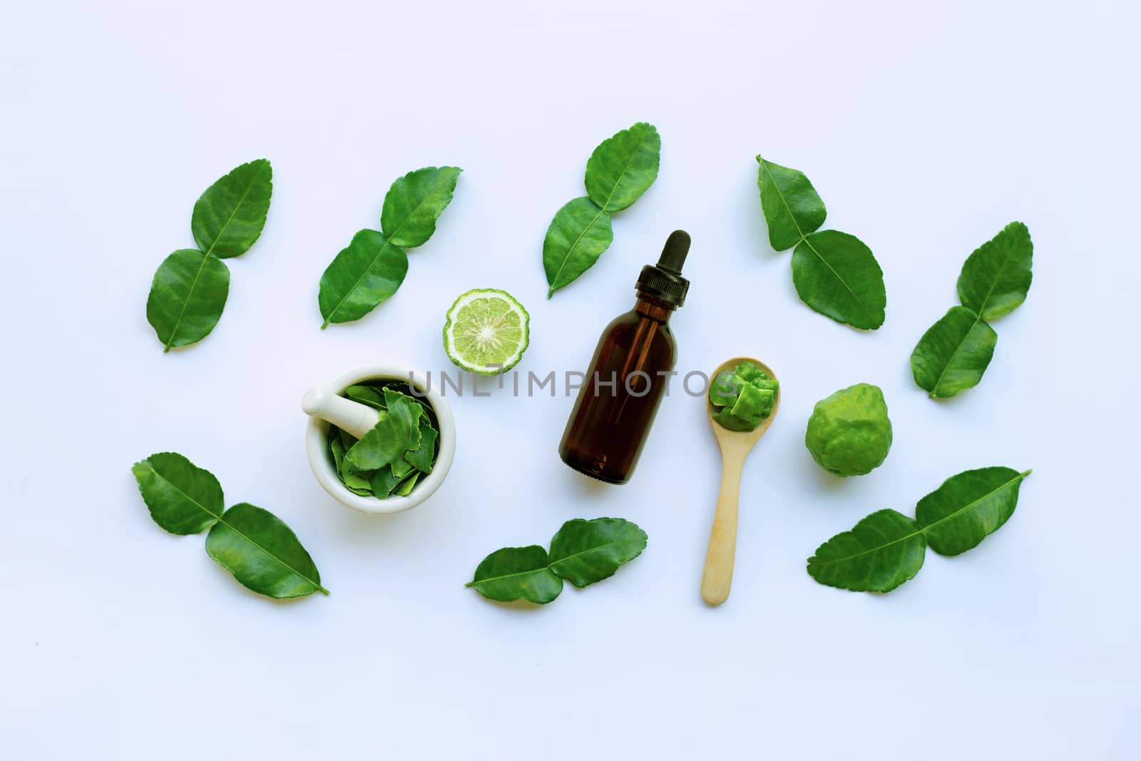 Bottle of essential oil and fesh bergamot fruit with leaves isolated on white background.