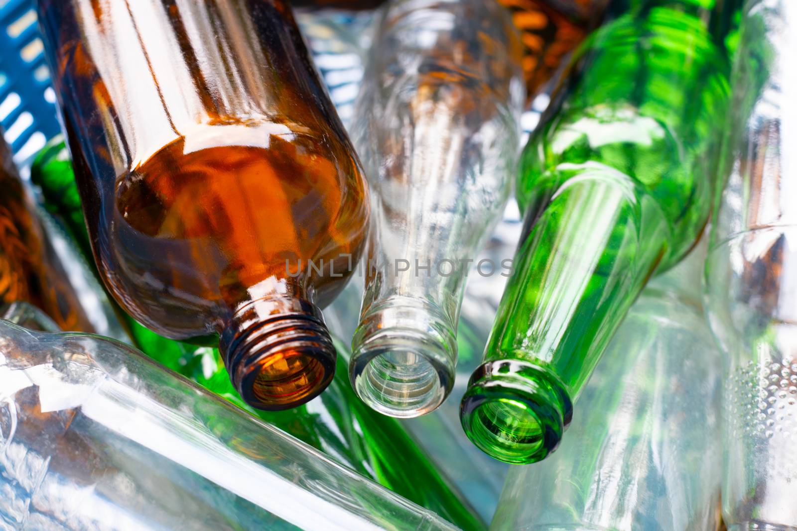 Glass bottles in blue waste basket.
